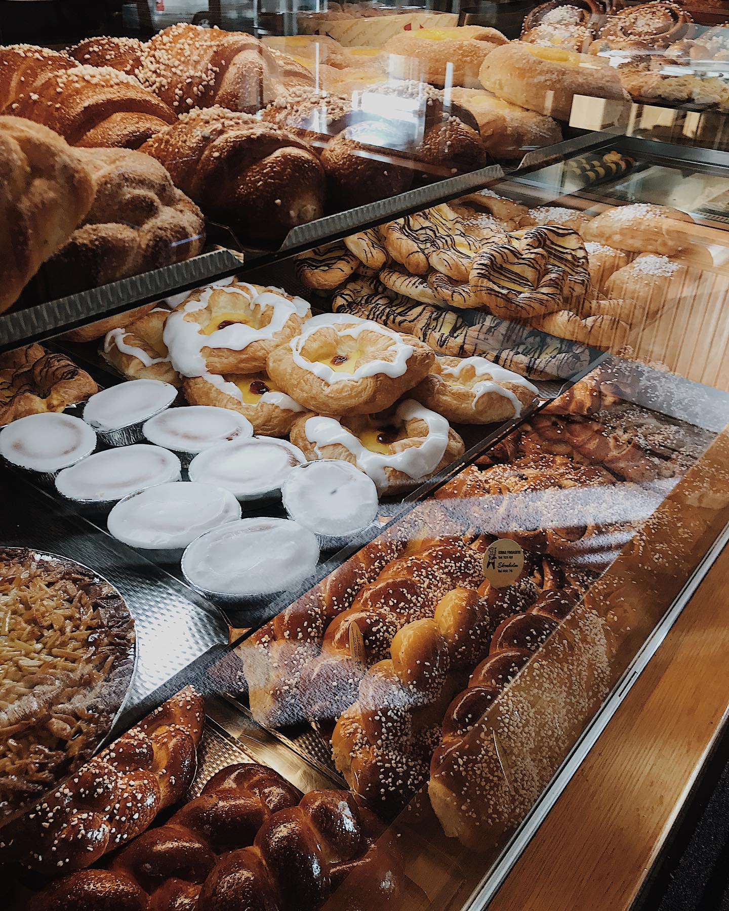 En närbild på utbudet av bullar, kakor och bakelser i en cafédisk