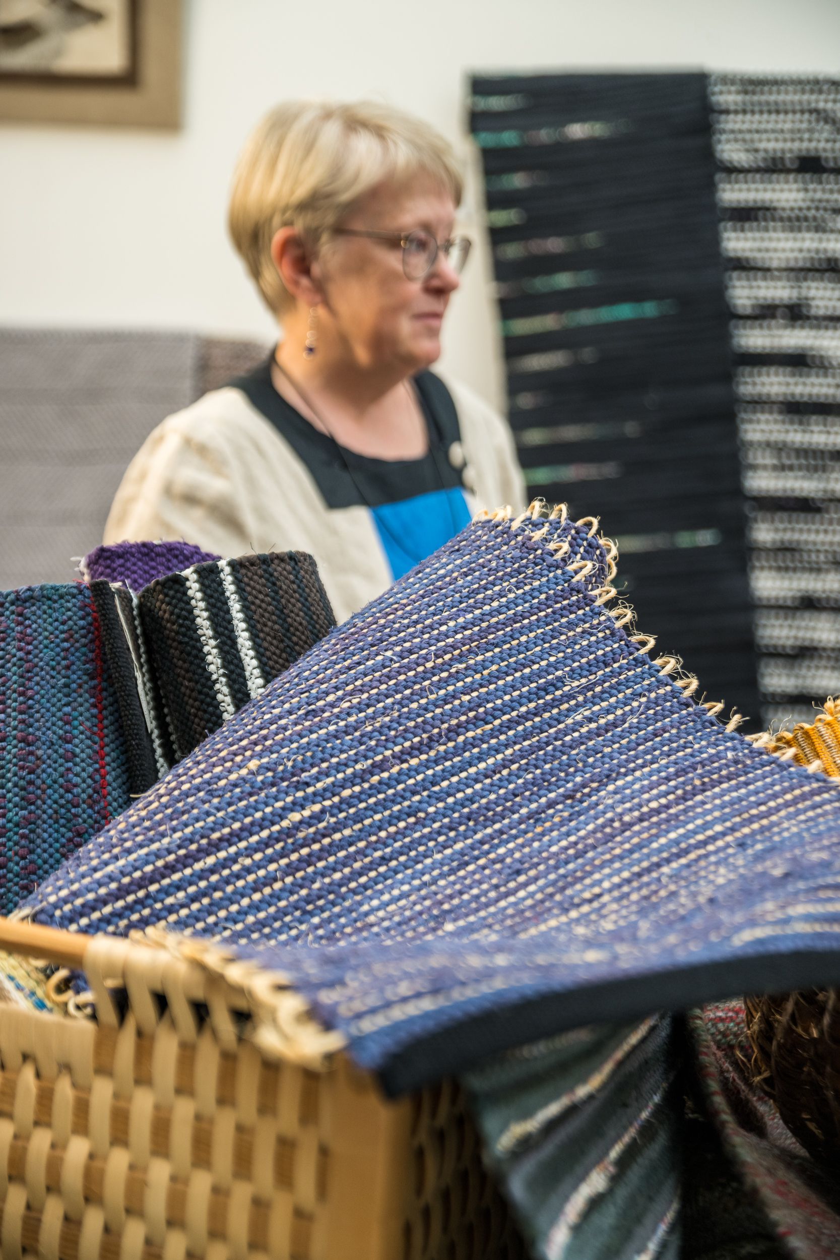 En bild på mattor i en korg. I bakgrunden skymtas en kvinna.