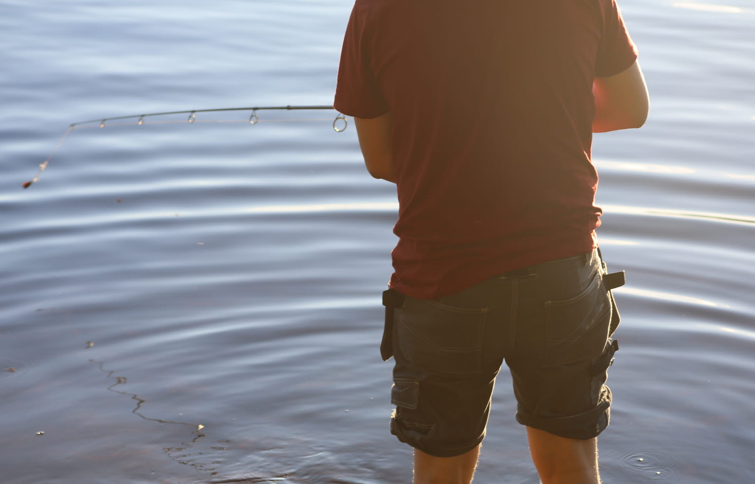 En man står i vattnet och fiskar.