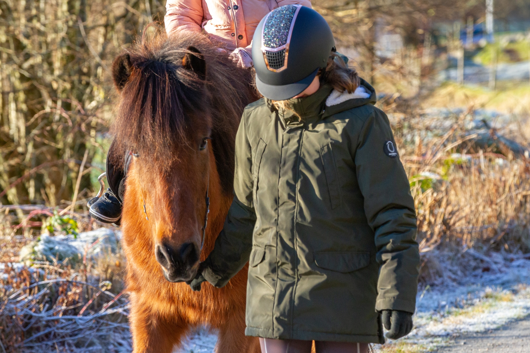 En flicka leder en häst med en liten ryttare