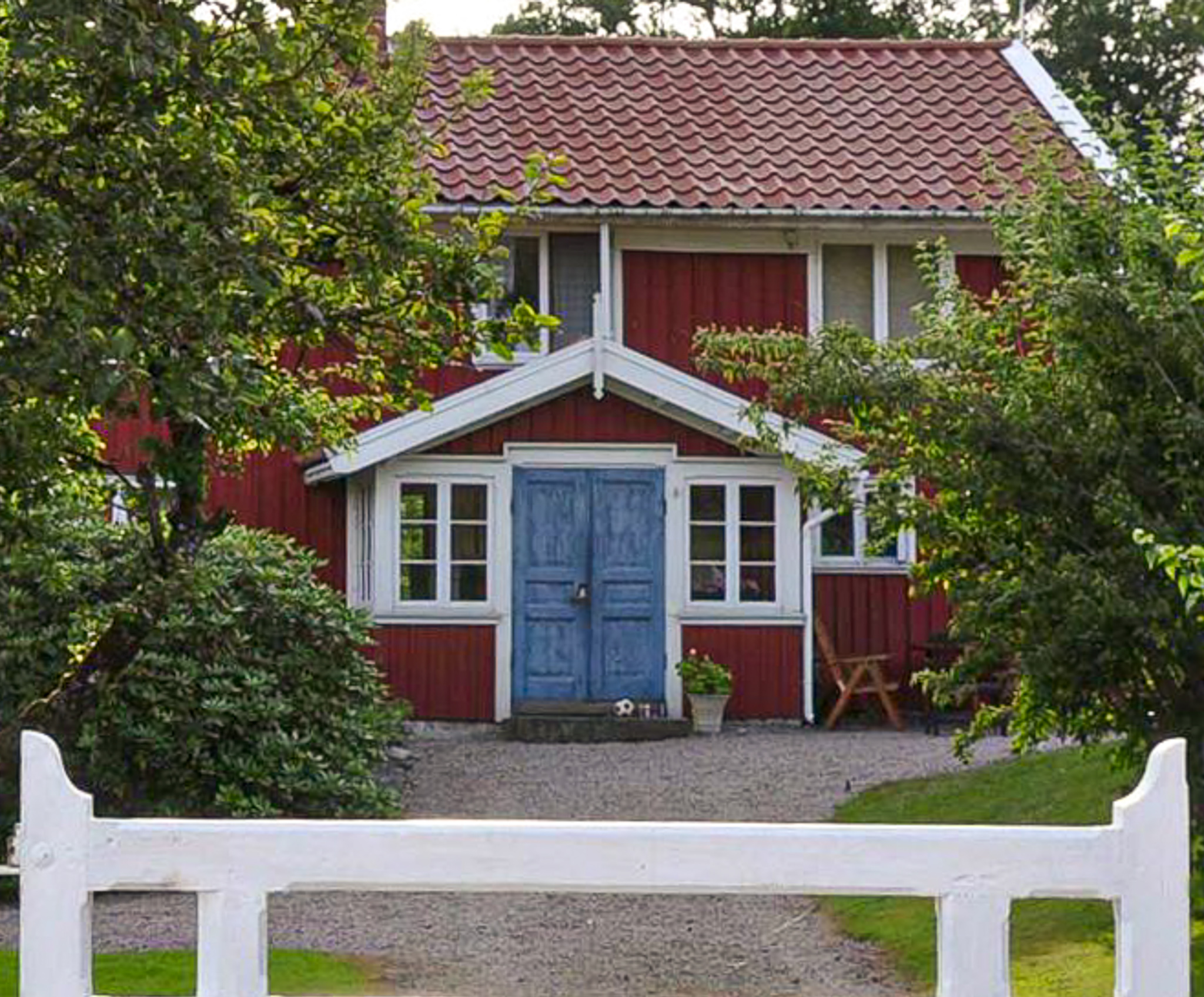En närbild på en glasveranda med blåa dubbeldörrar som sitter på ett äldre rött hus.