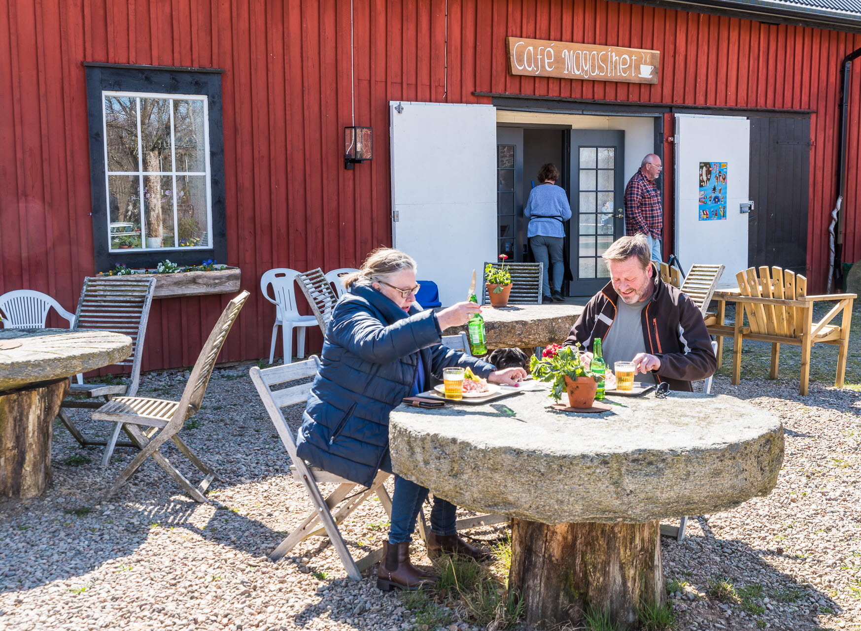 Två personer sitter och fikar utanför en gårdsbutik i Marks kommun