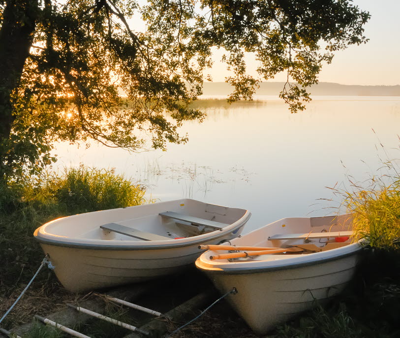 En bild på två båtar som ligger förtöjda vid strandkanten.