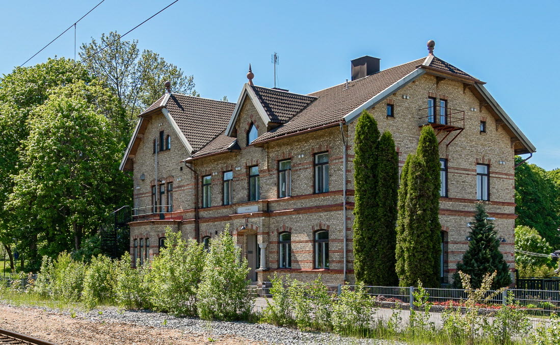 En bild på ett gult tegelhus i grön lummighet