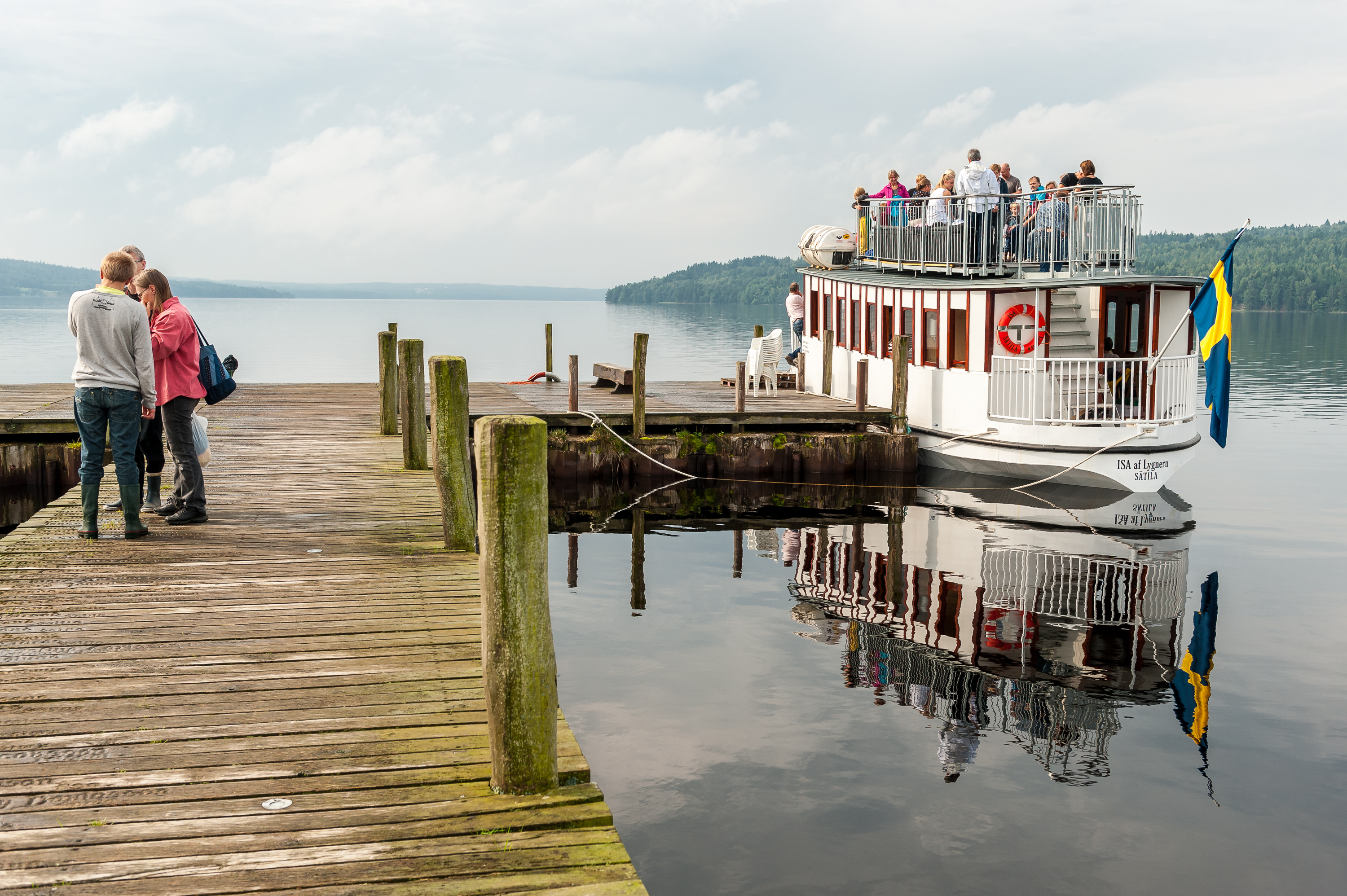 En båt ligger förtöjd vid en brygga där folk stigit ombord.