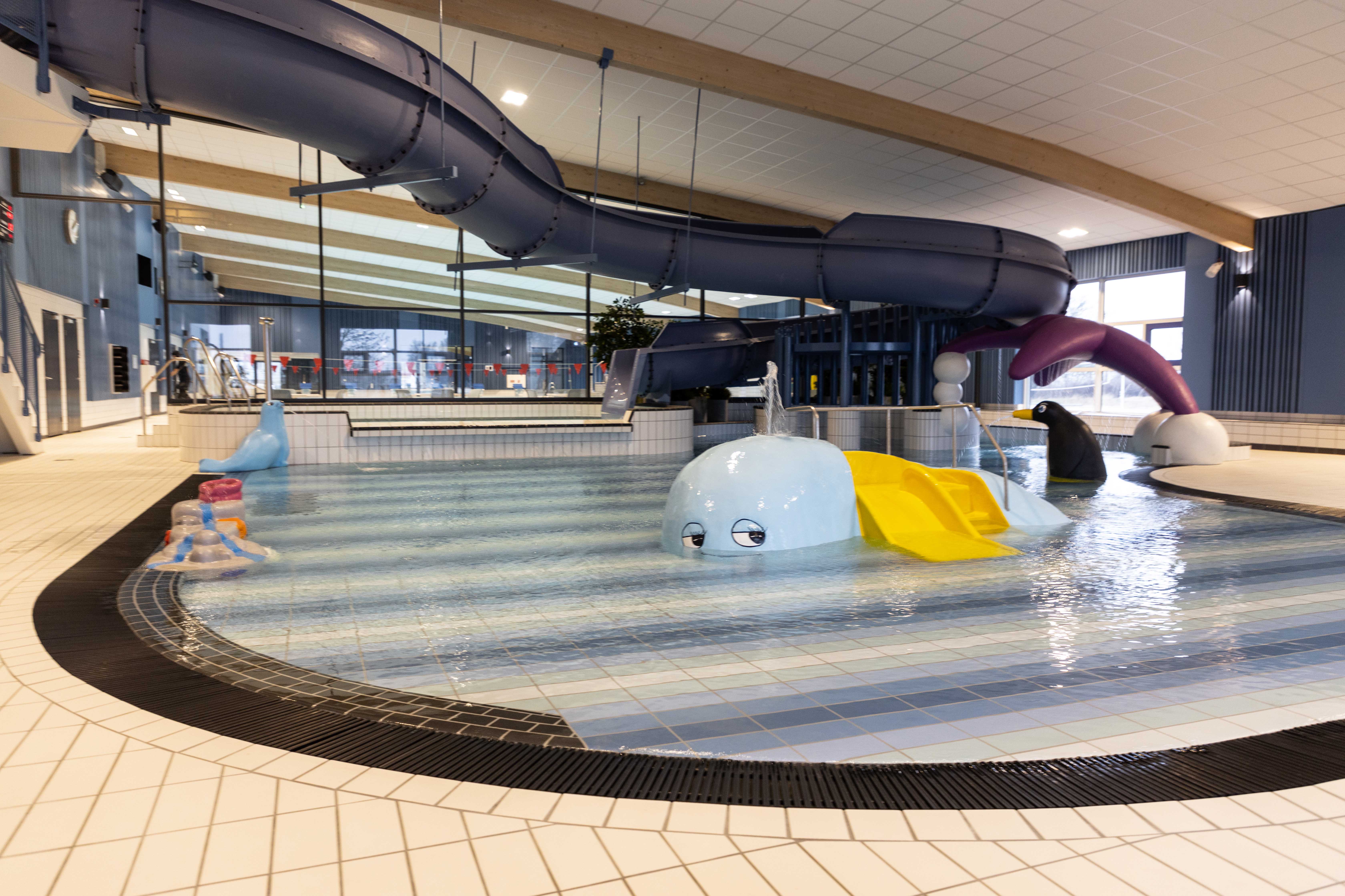 En bild på en simbassäng med rutschkana och fontän i.