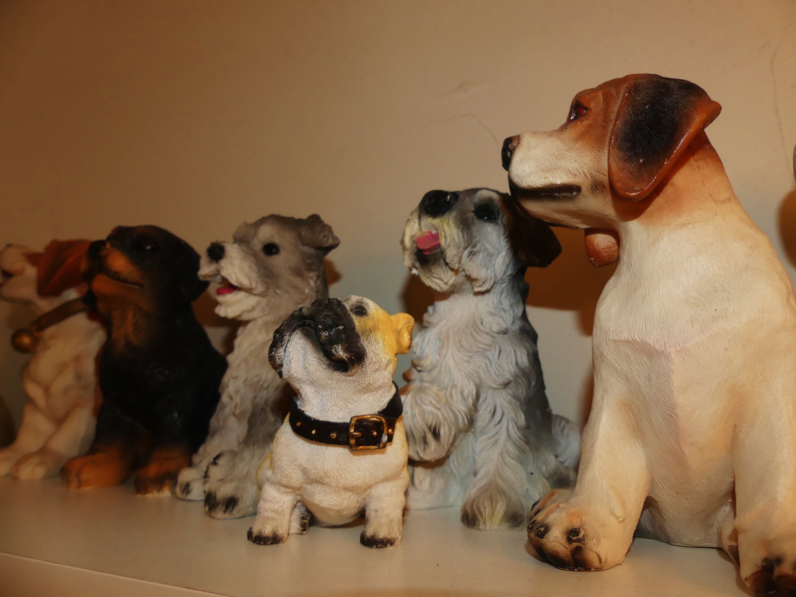 En närbild på prydnadshundar som står uppställda på en hylla.