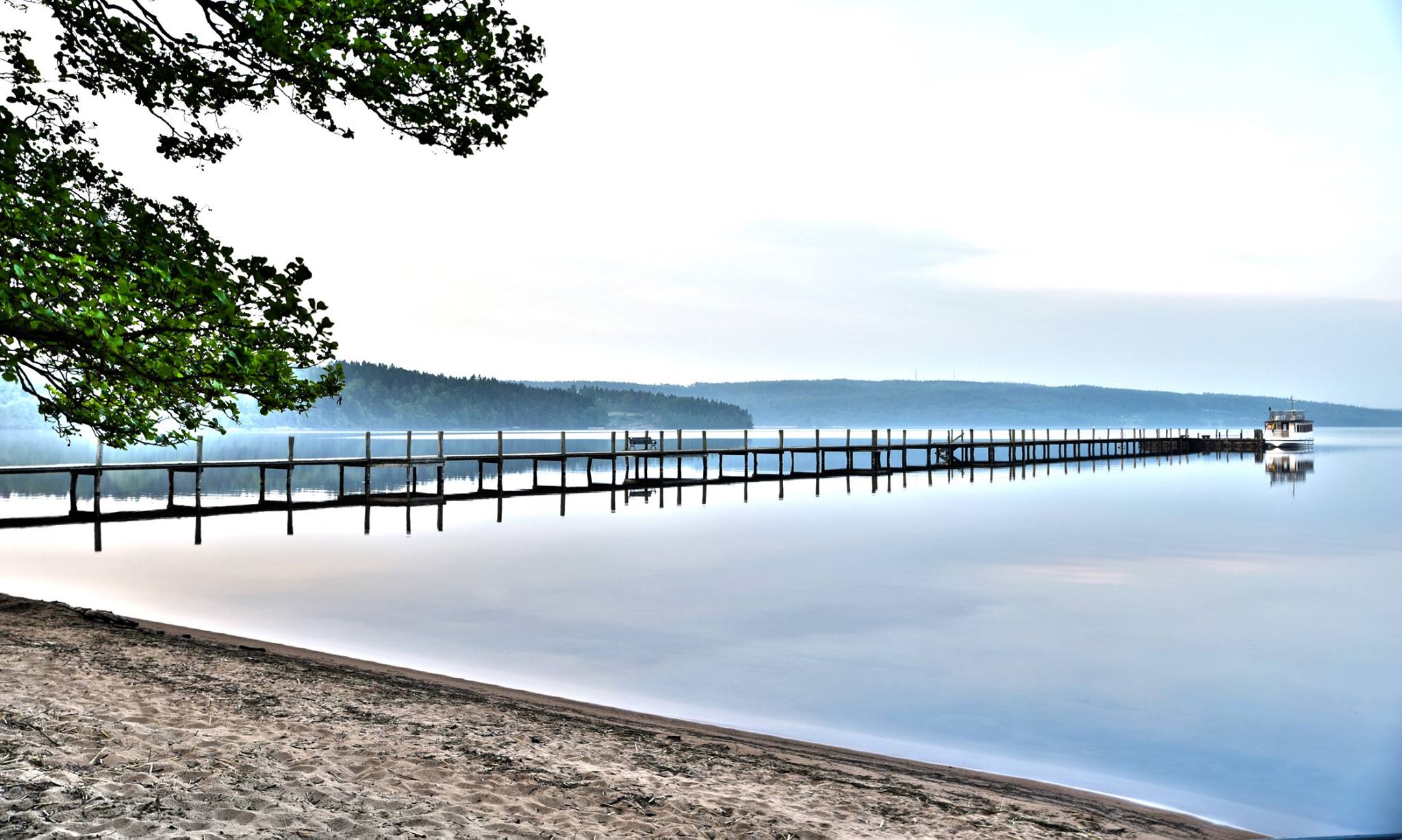 En lång brygga sträcker sig ut i en stor sjö.