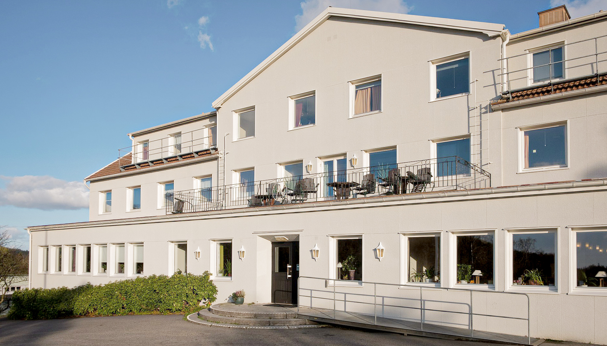 En närbild på en vitputsad husfasad med massor av fönster.