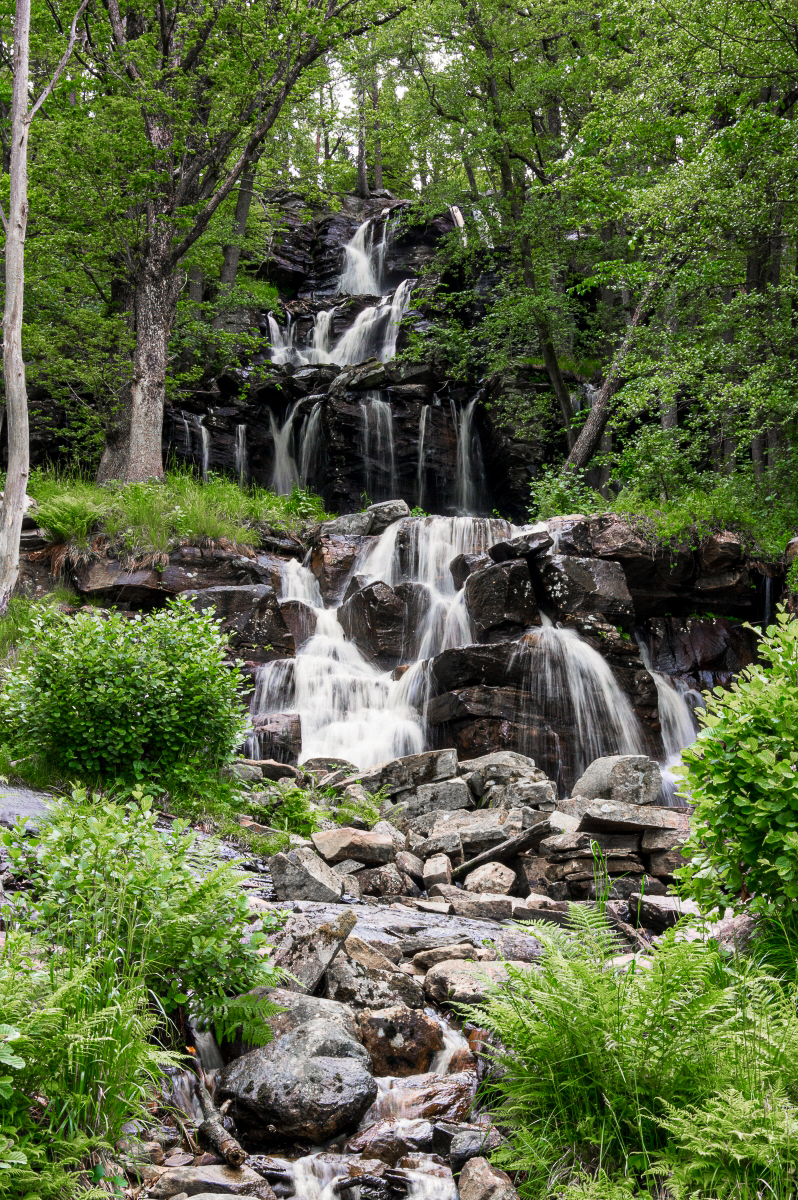 En bild på ett högt vattenfall där vattnet forsar ner för stenklipporna.
