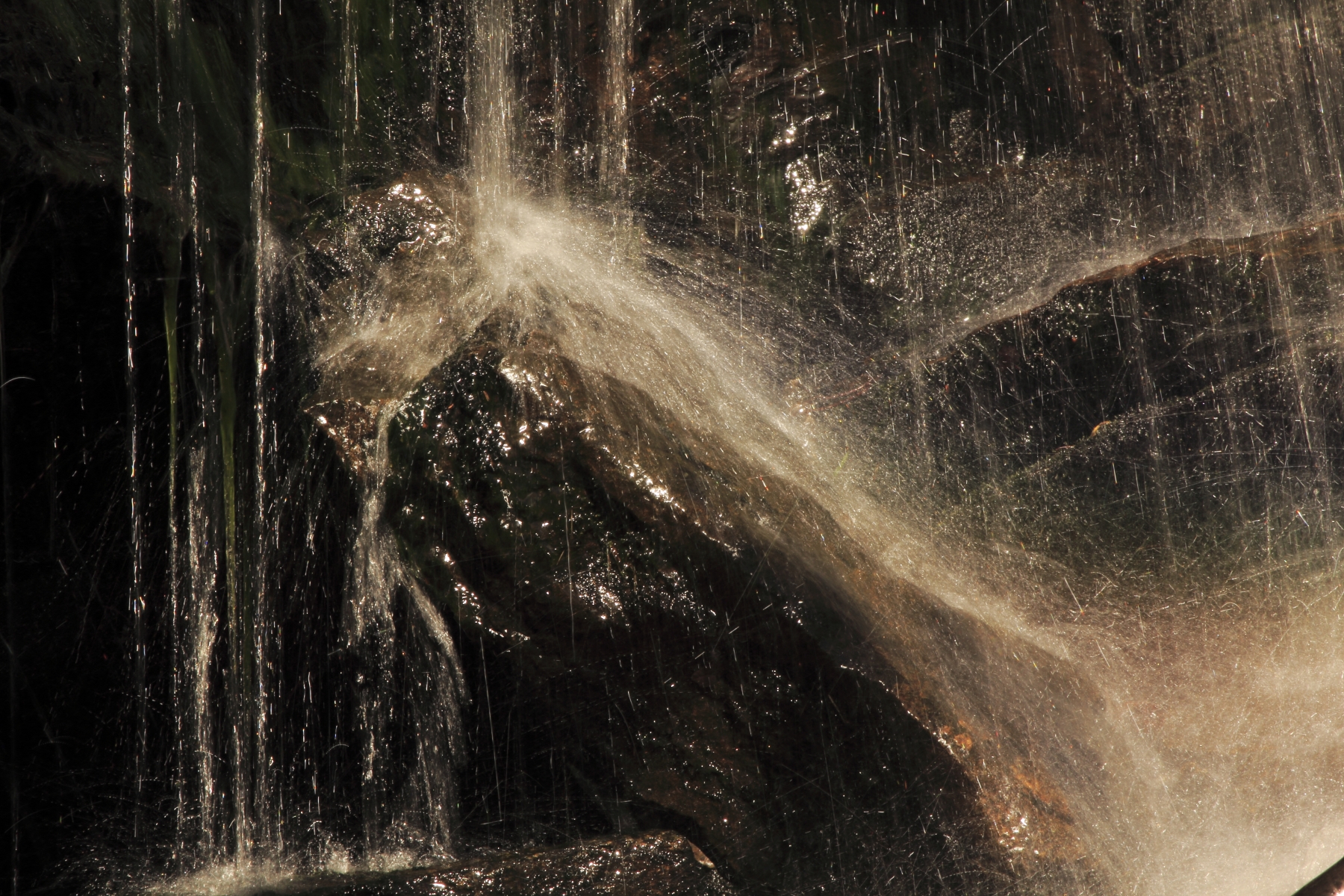 En bild på vatten som rinner ner över en sten så att det skvätter.