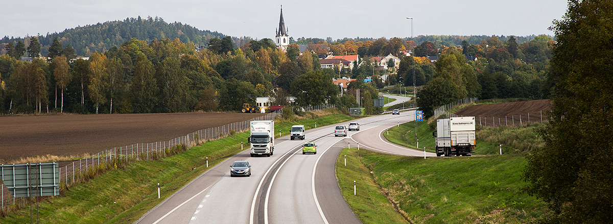 En bild på en riksväg med en stad i bakgrunden.