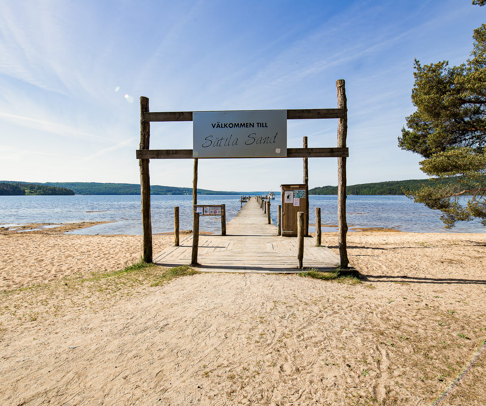 En bild på en stor sandstrand och en gedigen brygga som leder rakt ut i sjön Lygnern - den största sjön i Marks kommun.