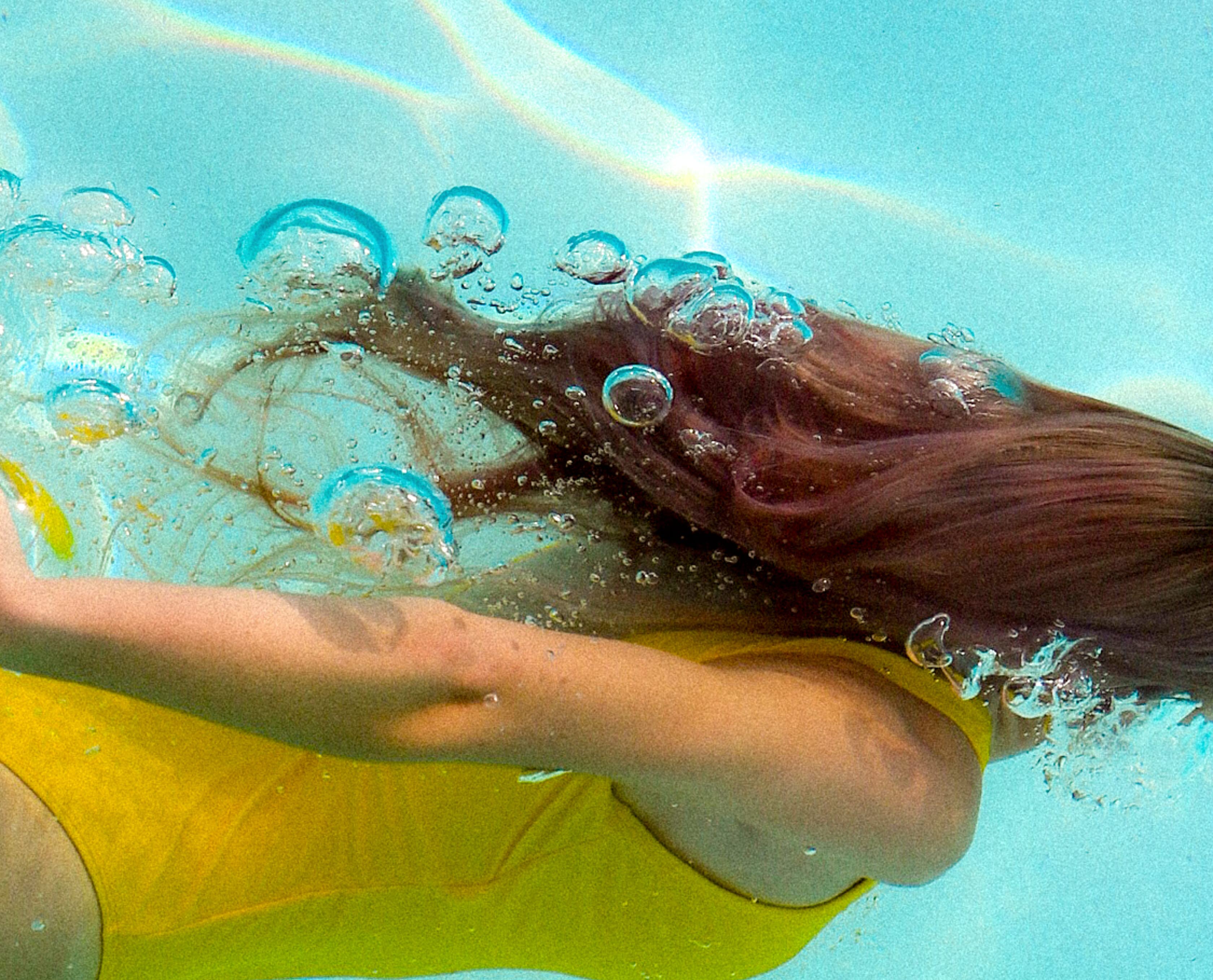 En bild på en flicka som simmar under vattnet i en simbassäng.