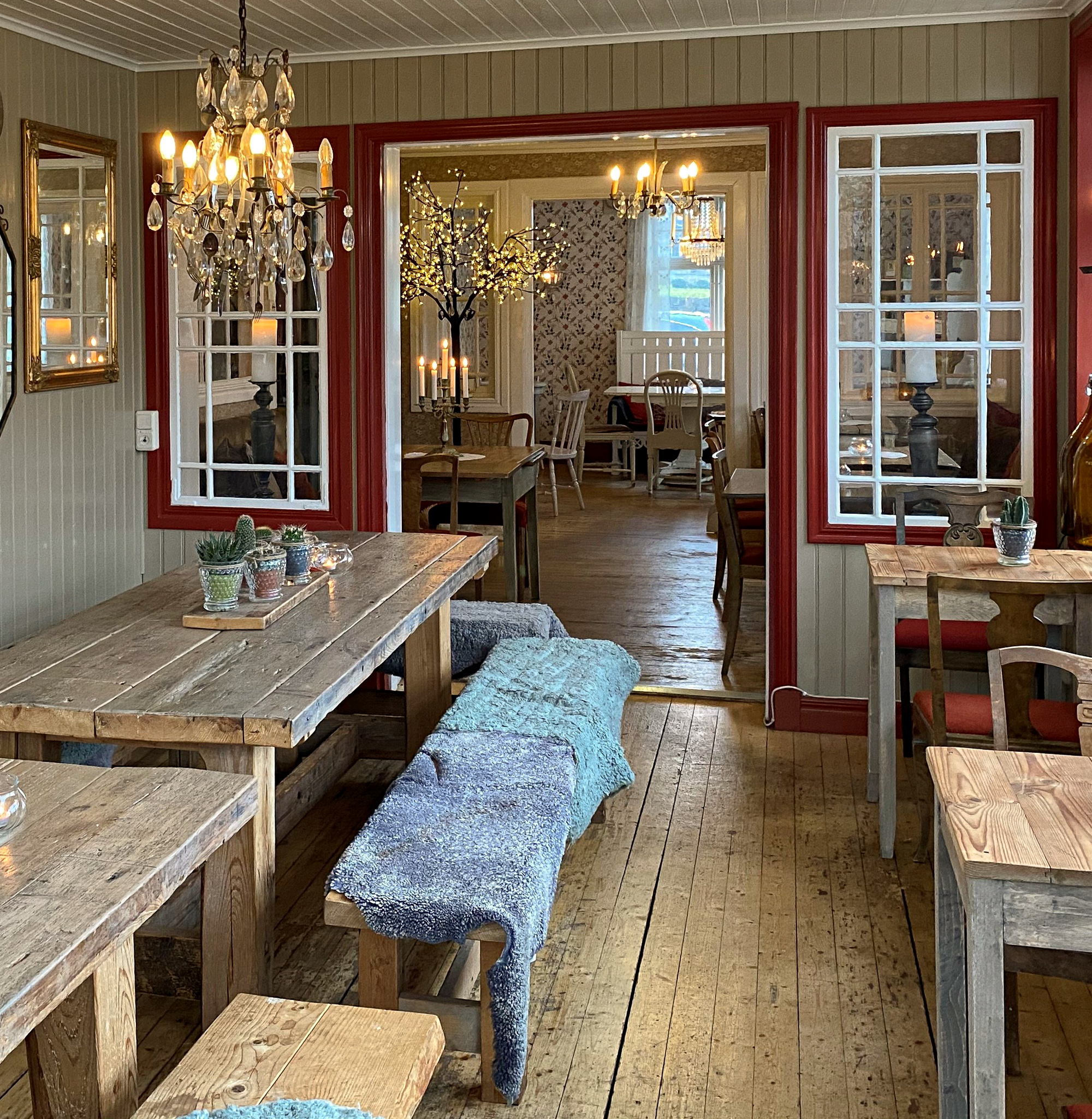 En bild inifrån ett café där mängder av små fikabord står utplacerade under kristallkronor som hänger från taket.