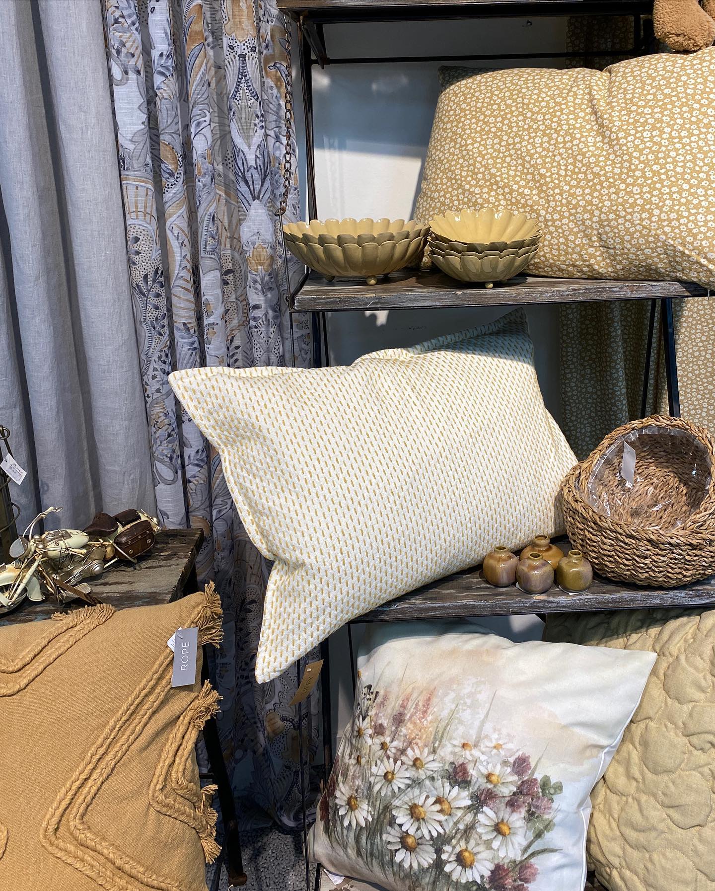 En närbild på en butikshylla där skålar av porslin, puffade kuddar och små korgar står uppradade.