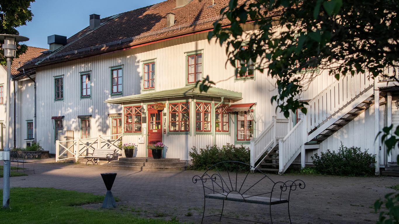 En bild på ett stort vitt hus av trä med röda och gröna detaljer runt fönstren.