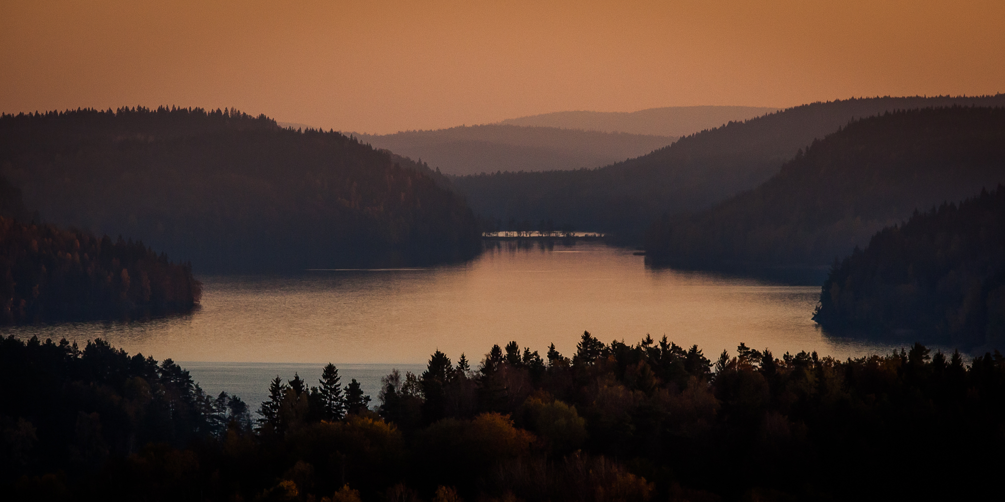 En magisk utsiktsbild över vatten, berg och solnedgång