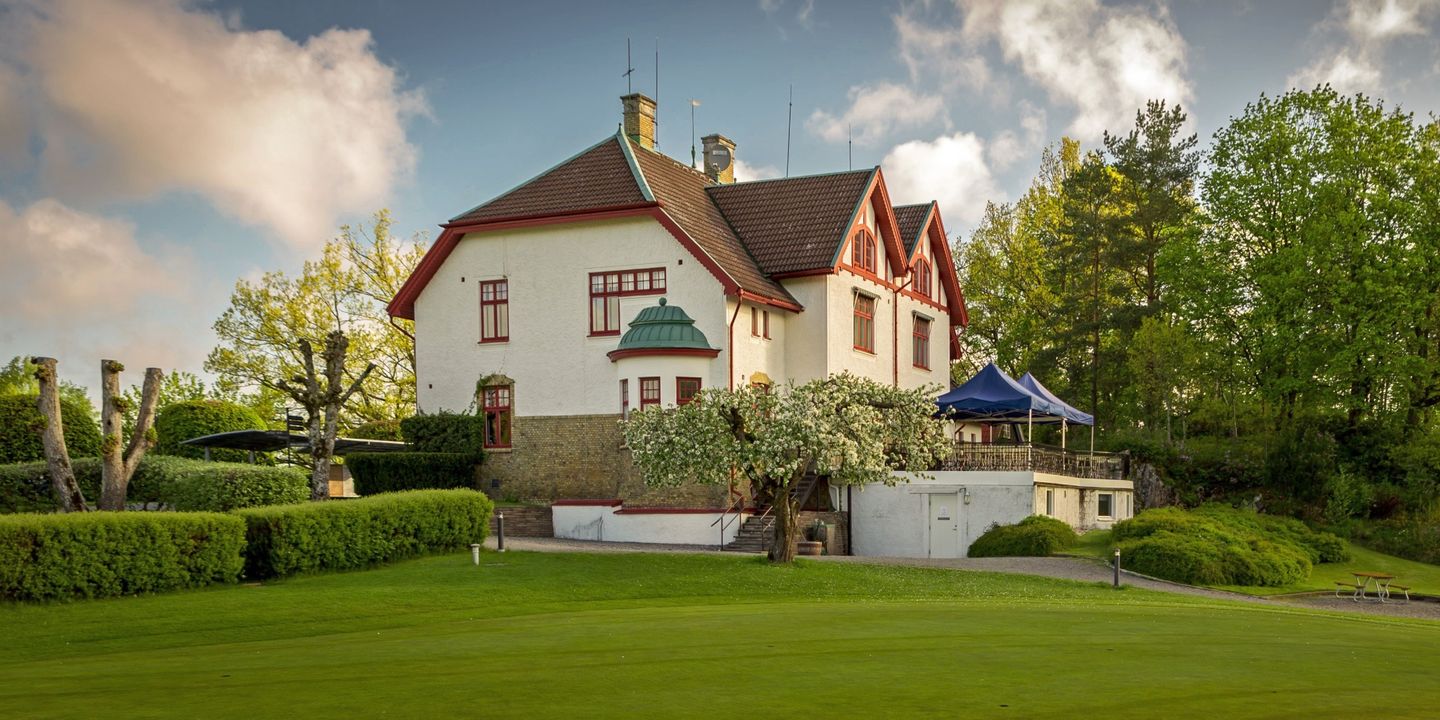 En bild på ett vitt hus av sten som är omgivet av en grön gräsmatta.