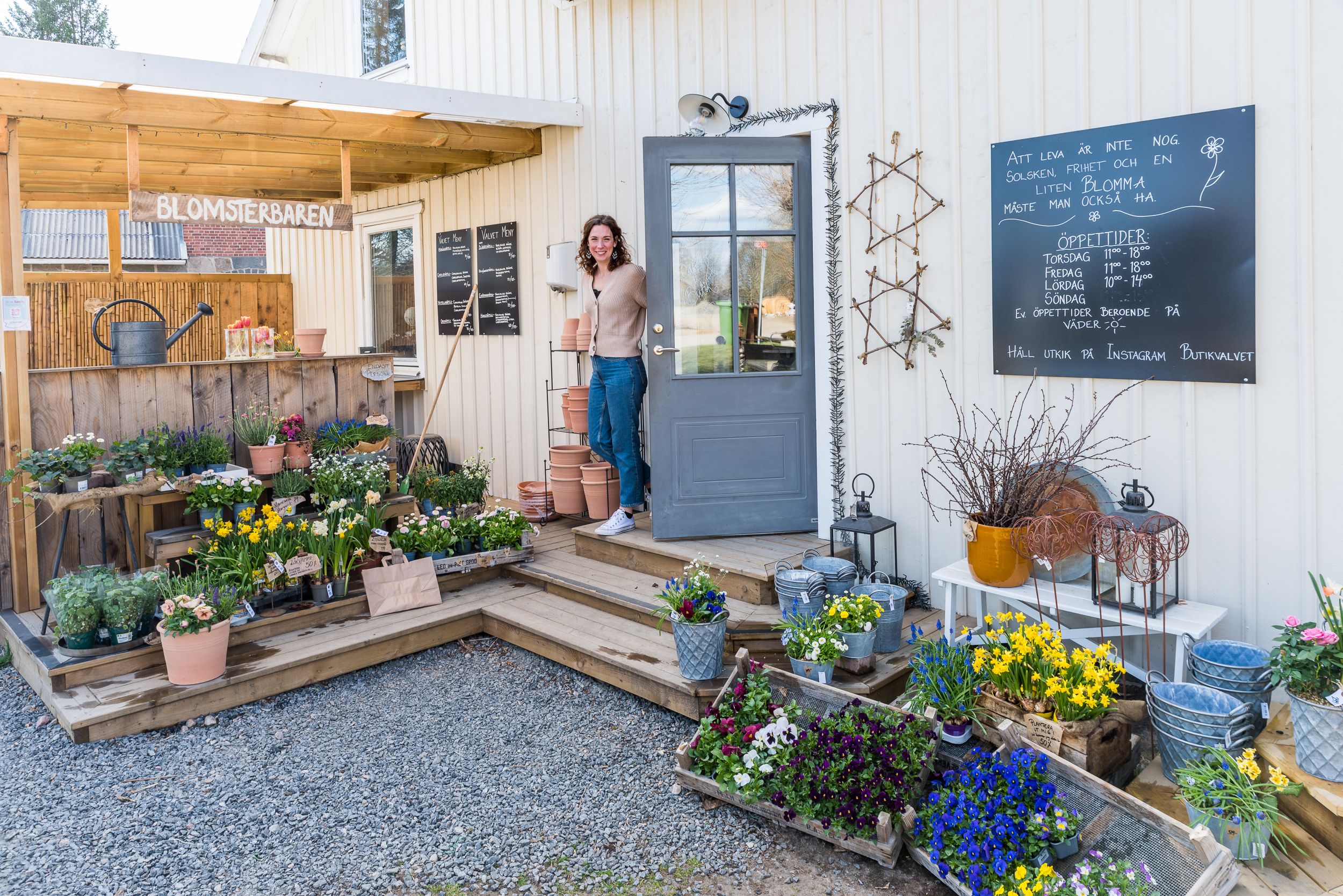 En bild på entrén in till en liten butik. På trappan står mänger av blommor och arrangemang.