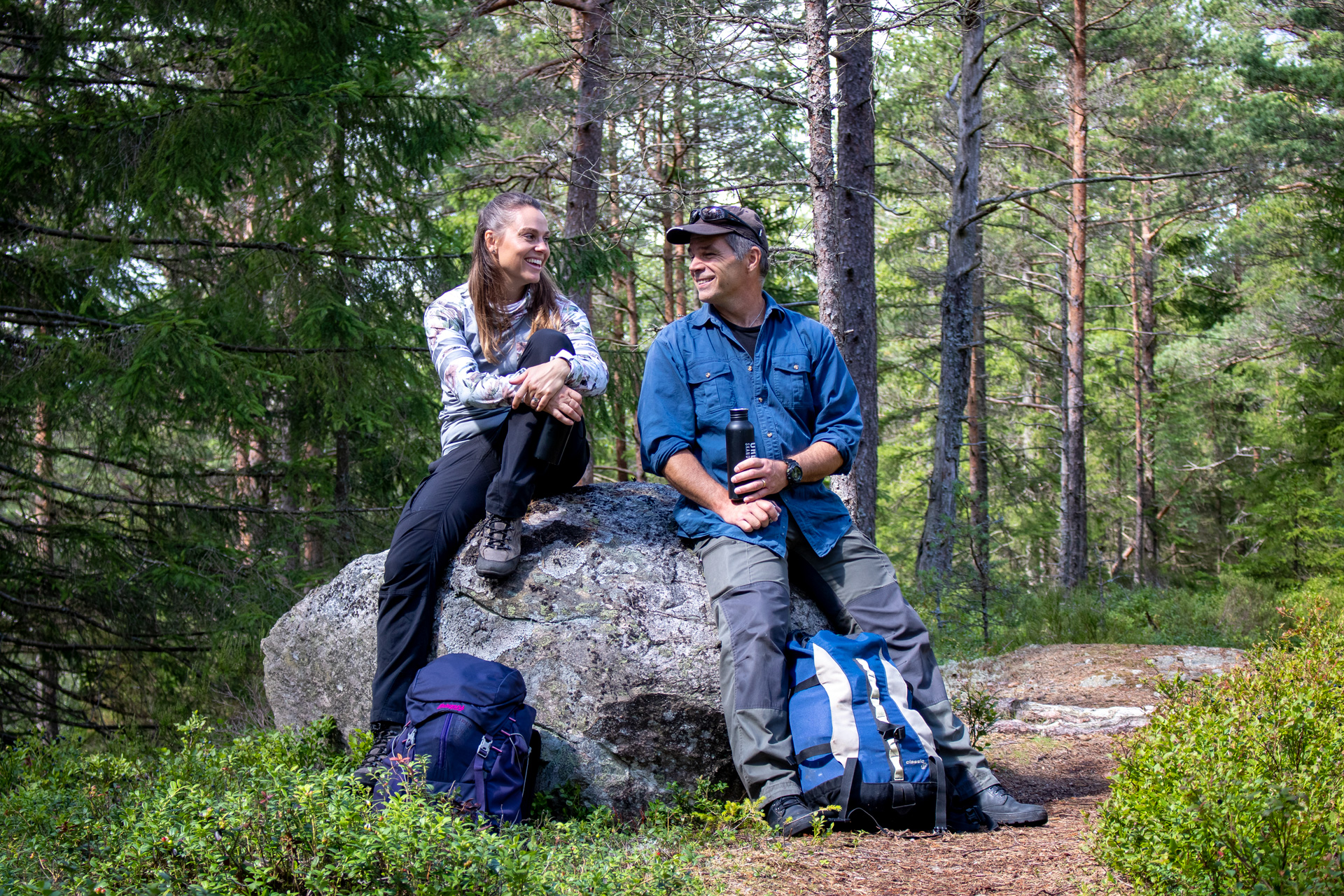 Två personer sitter på en sten i skogen.