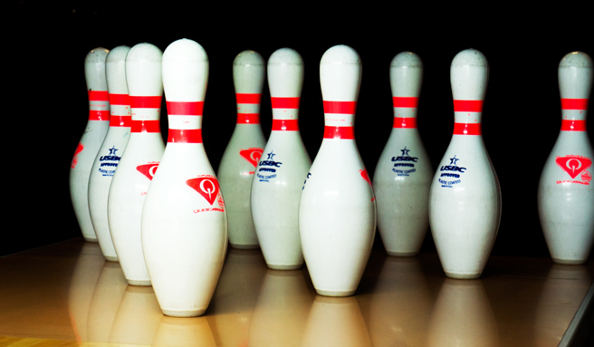 Vita bowlingkäglor med röda ränder står uppställda intill varandra redo för spel.