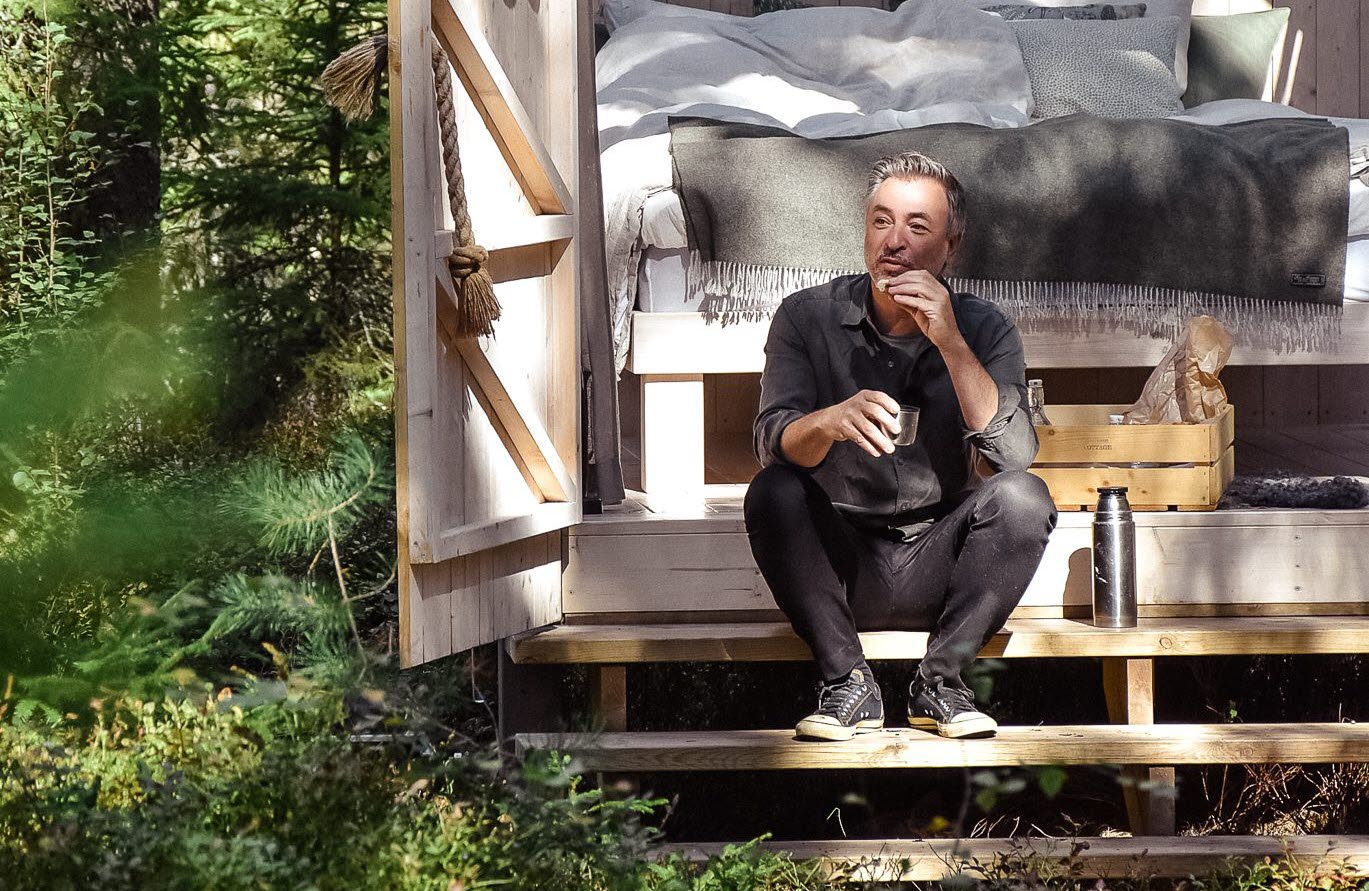 Kocken Tareq Taylor sittandes på en trappa vid en stuga hos Ericsson Cottage.