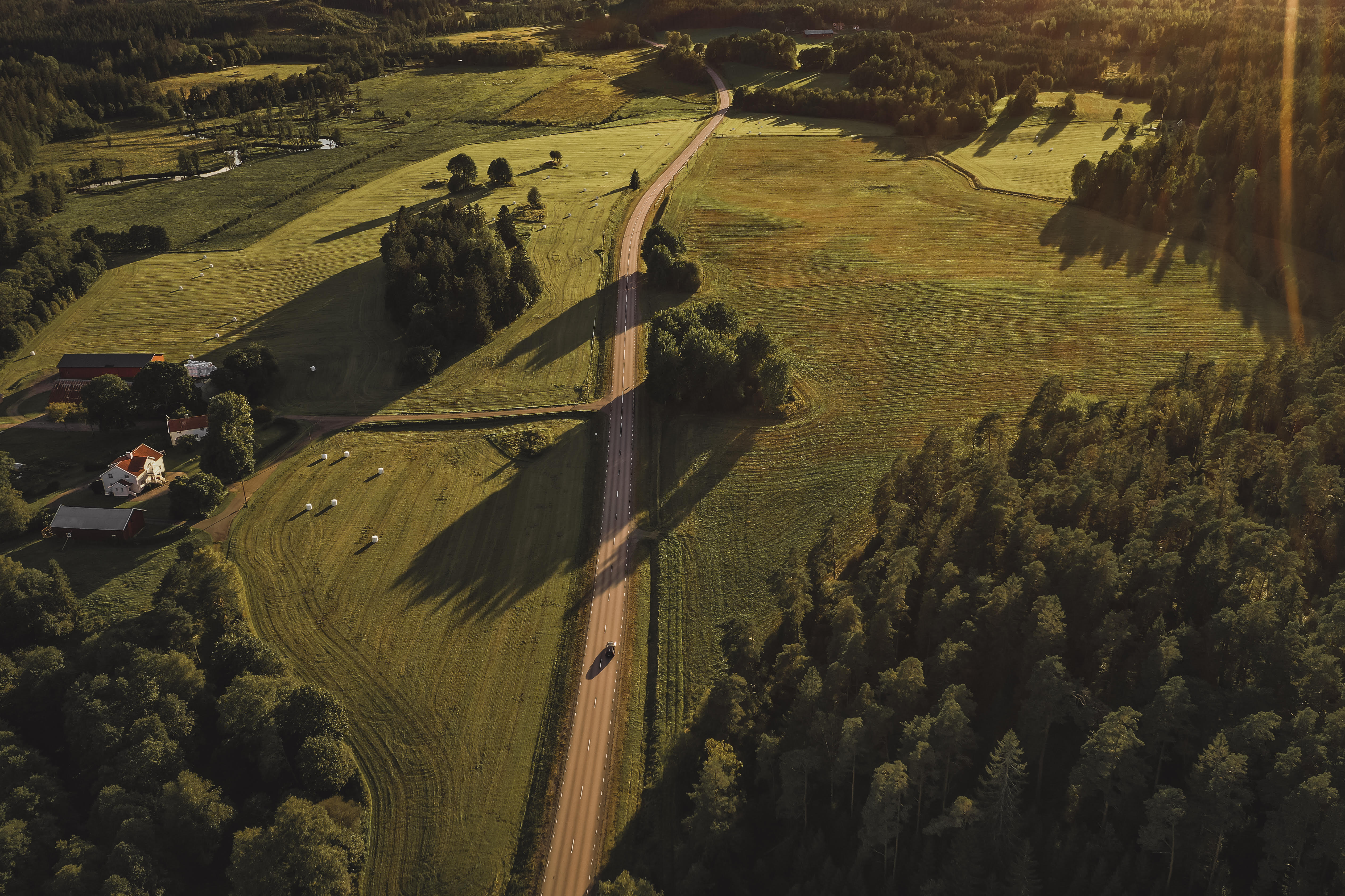 Landskapsbild uppifrån. En väg med gröna ängar runt om.