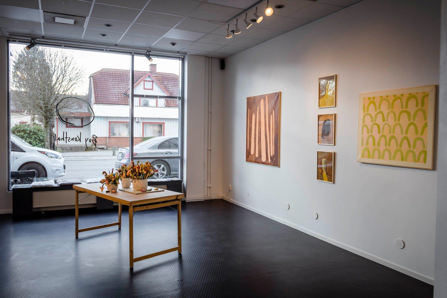 Picture from an exhibition hall, with five paintings in different sizes.