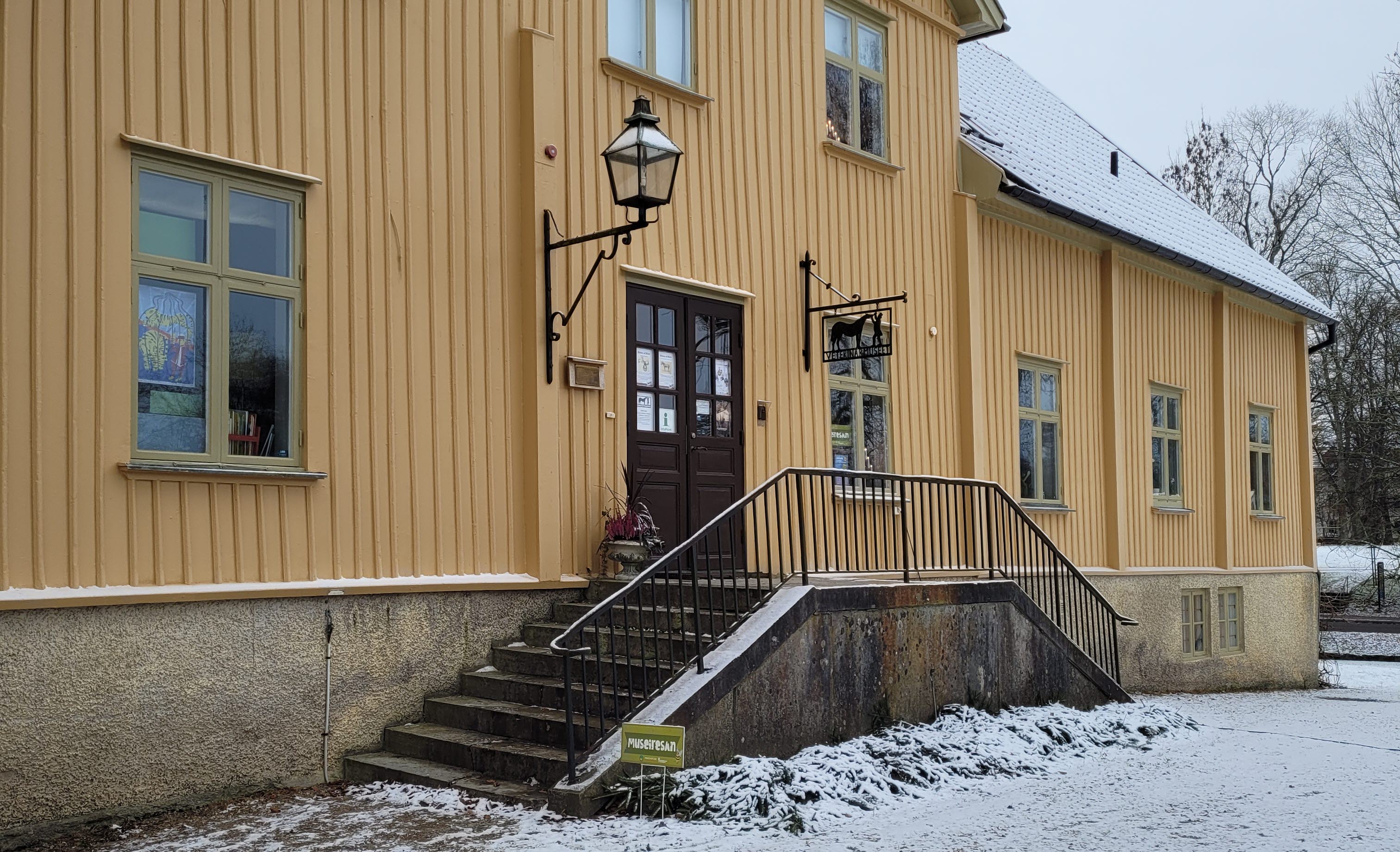 En stor gul träbyggnad med en stentrappa.