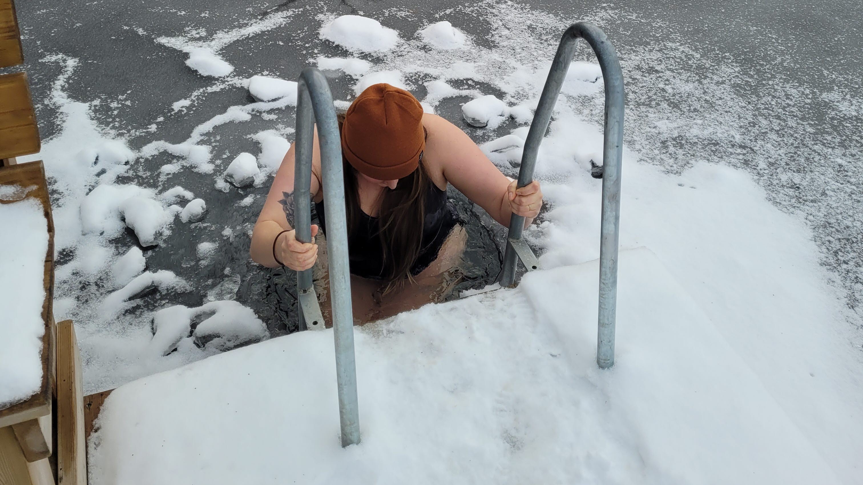 En person badar från en stege i en isvak.