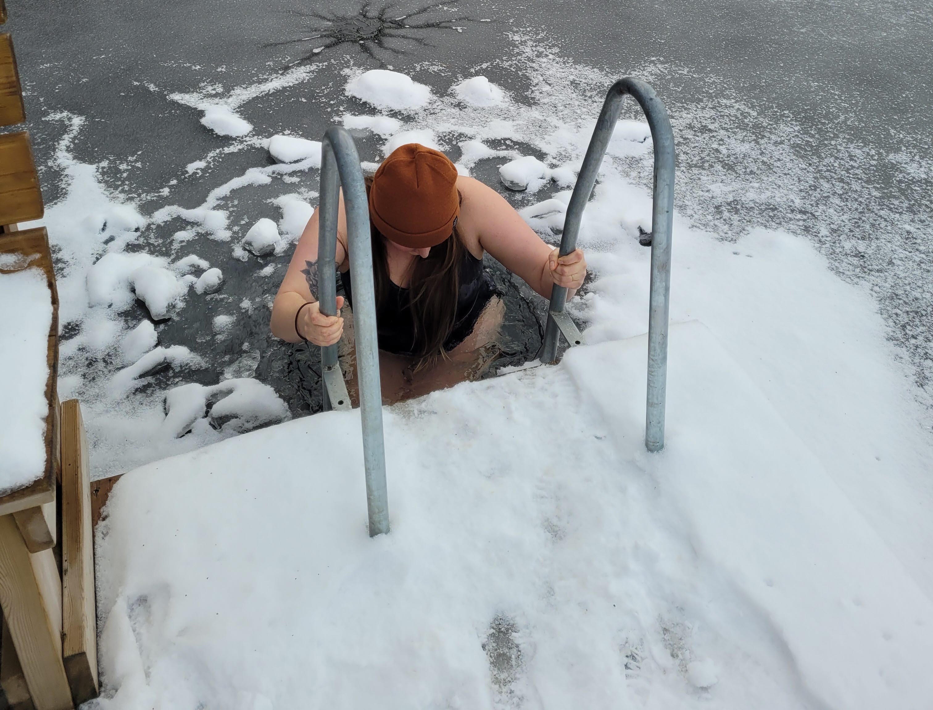 En person badar från en stege i en isvak.