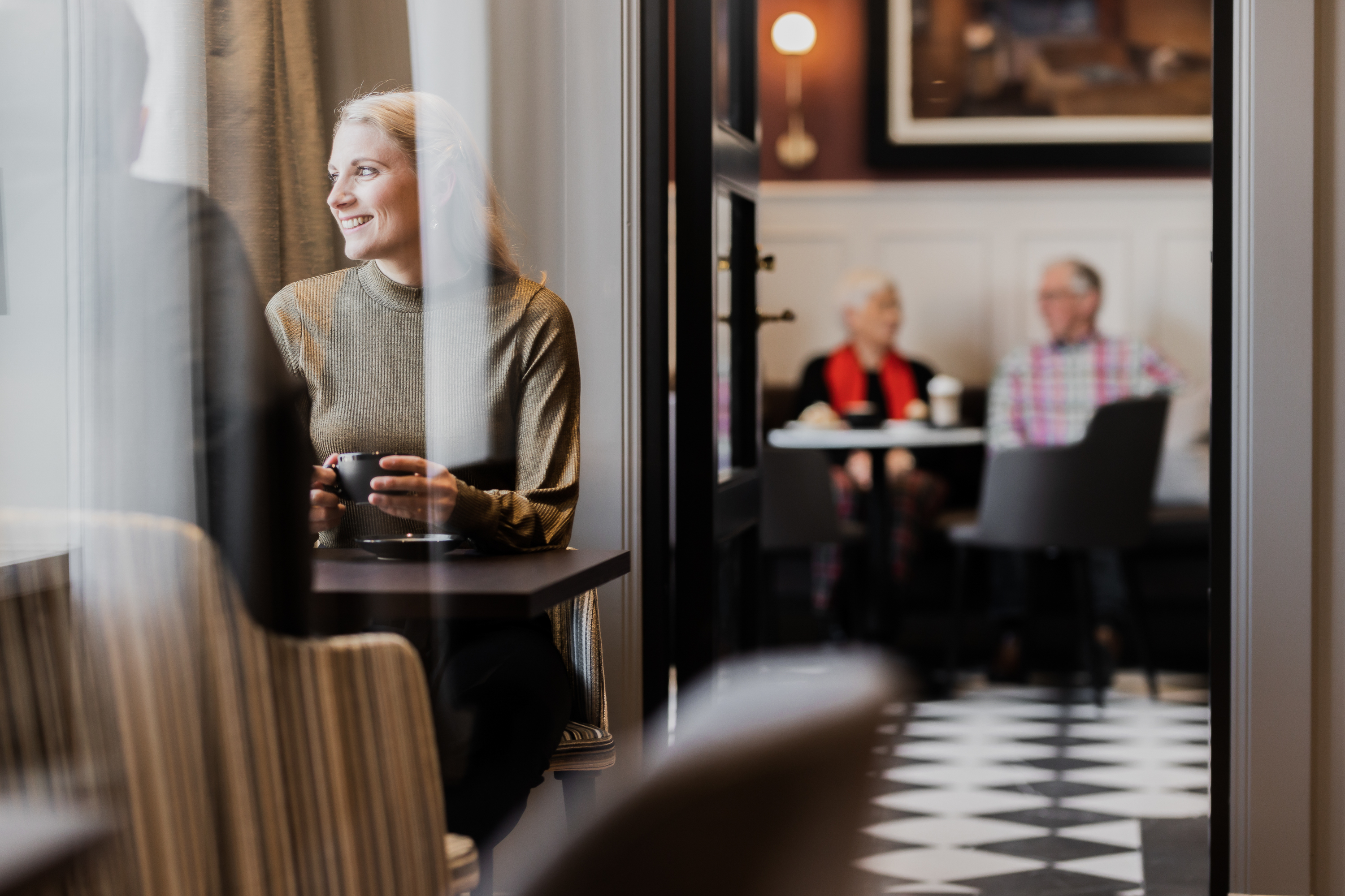 Cafémiljö med personer som sitter och fikar och samtalar.