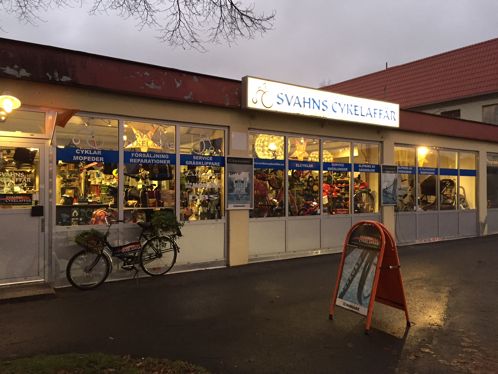 Svahns cykelaffär. Röd skylt i förgrunden, cykelaffär i bakgrunden, cykel lutad mot huset. 