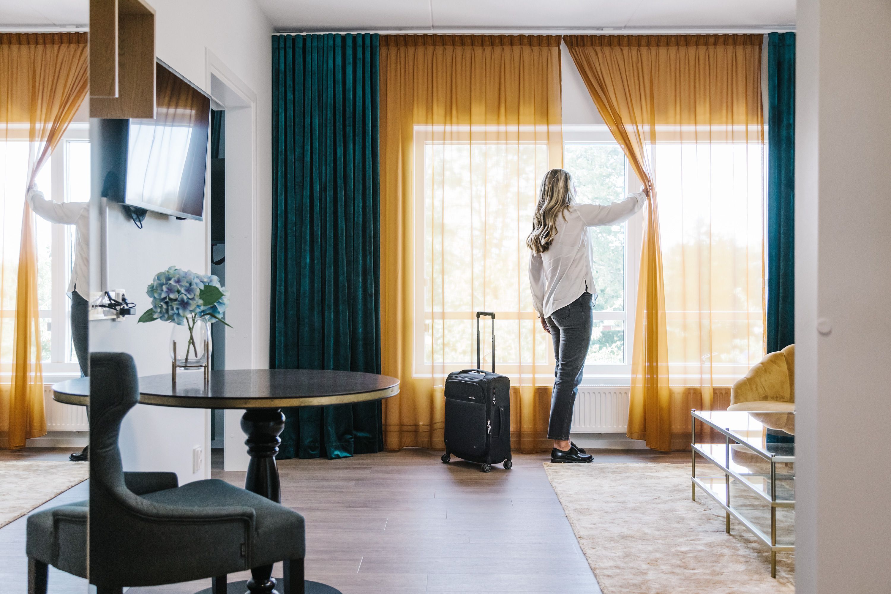 Ett hotellrum där en kvinna står och tittar ut genom fönstret