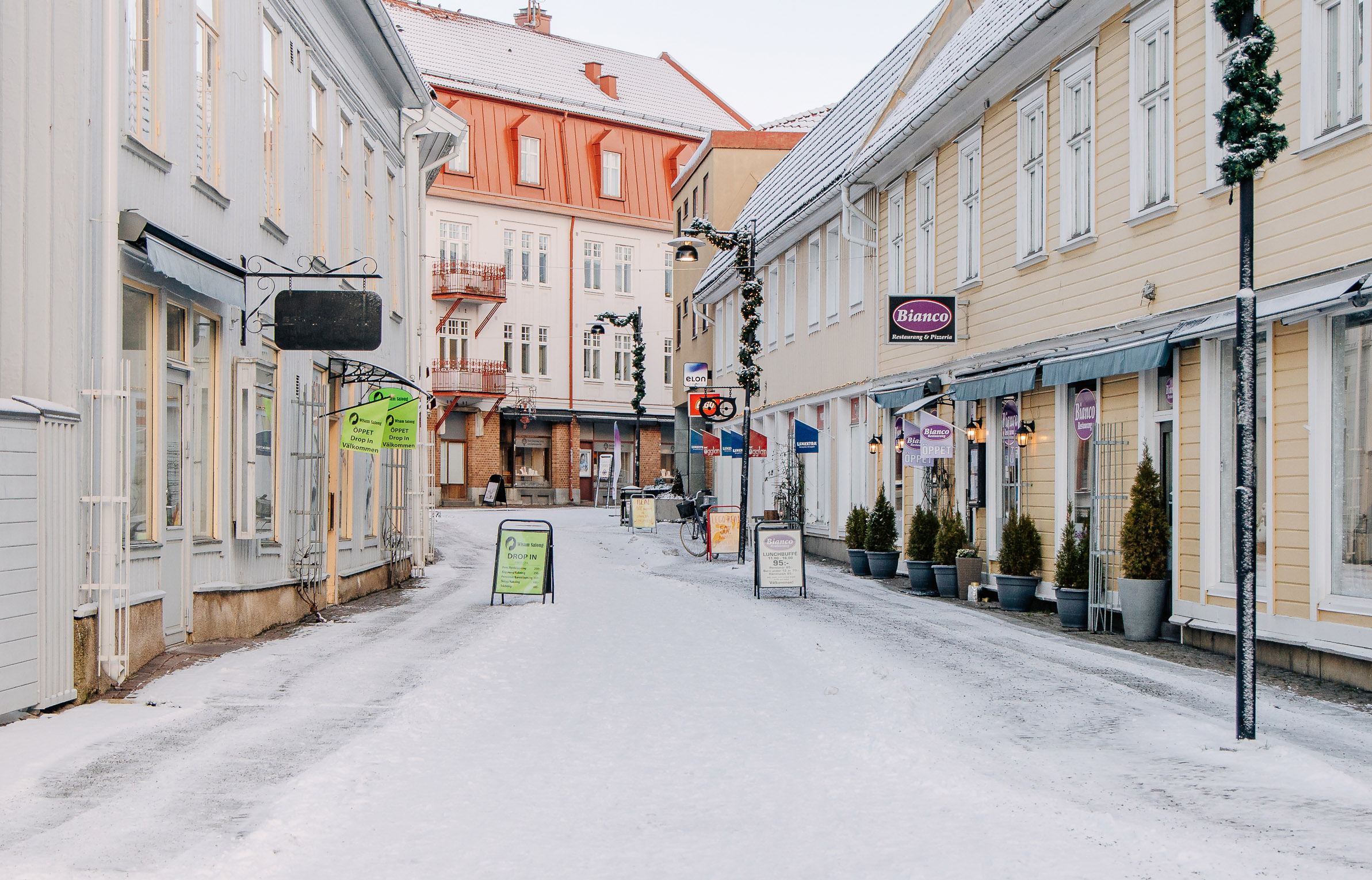 En vintrig gata i stadsmiljö kantad av ljusgula hus.