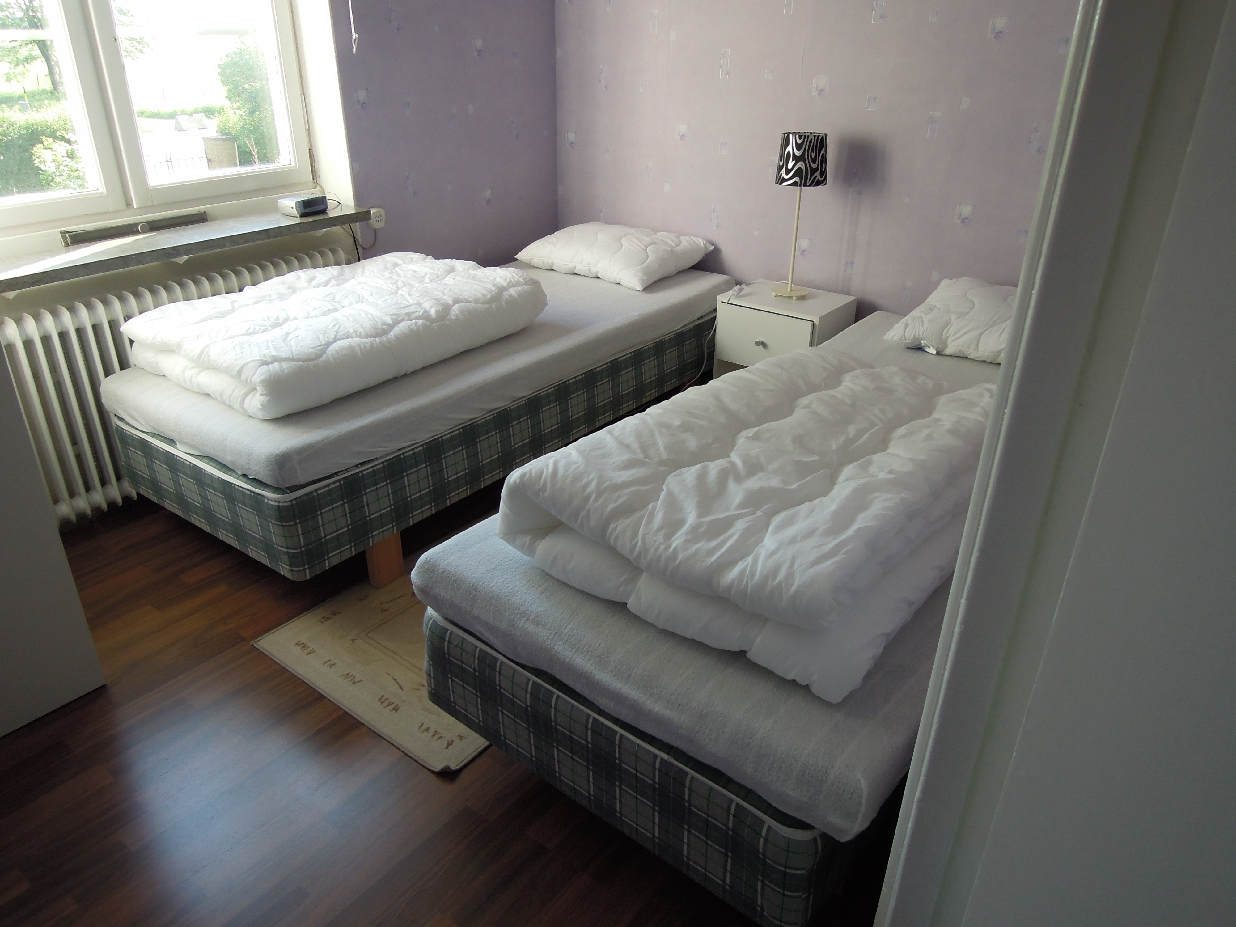 Ett sovrum med två enkelsängar. Rummet har ljusa väggar.