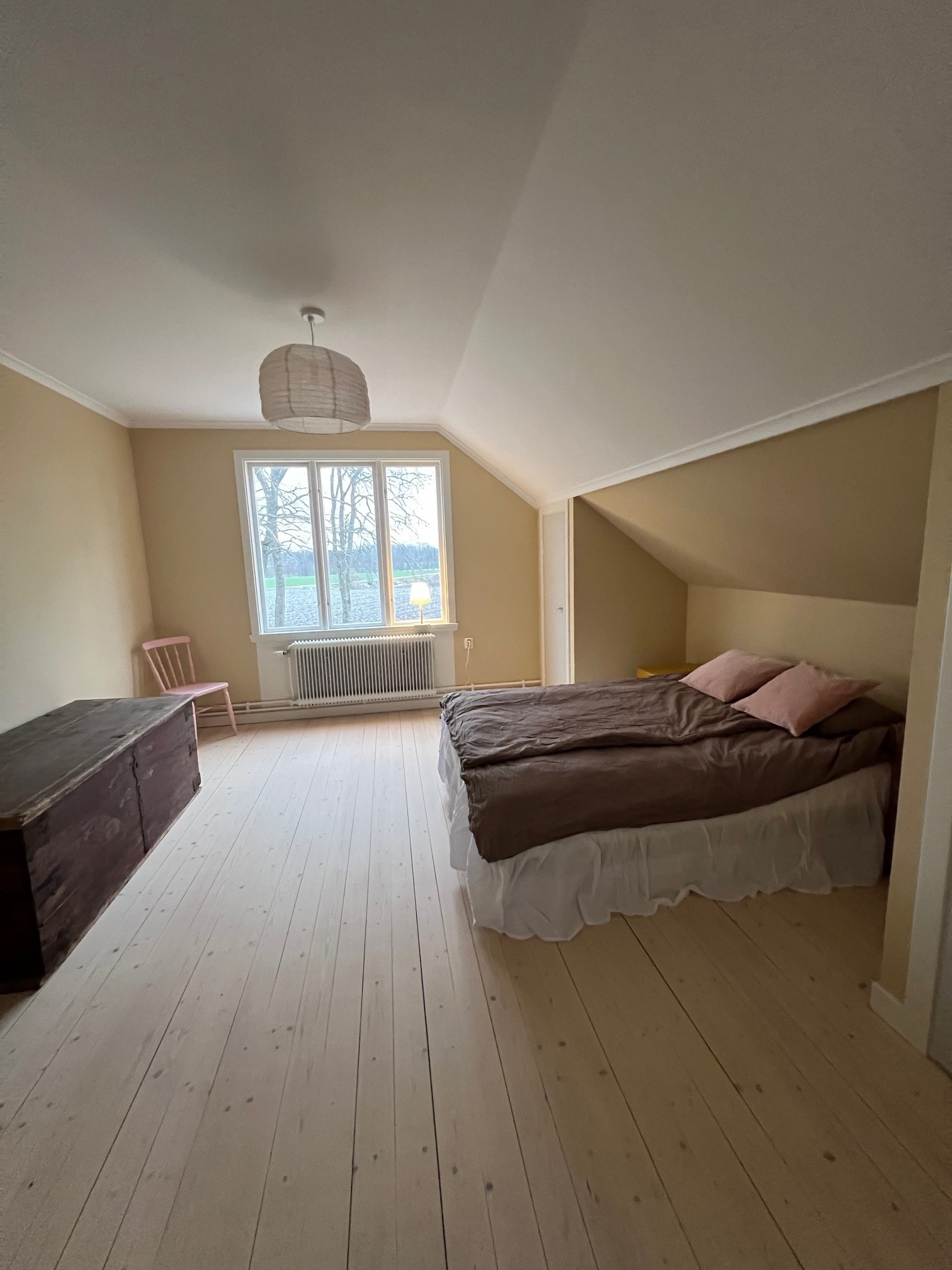 Ett sovrum på övervåning med dubbelsäng, ljusa trägolv