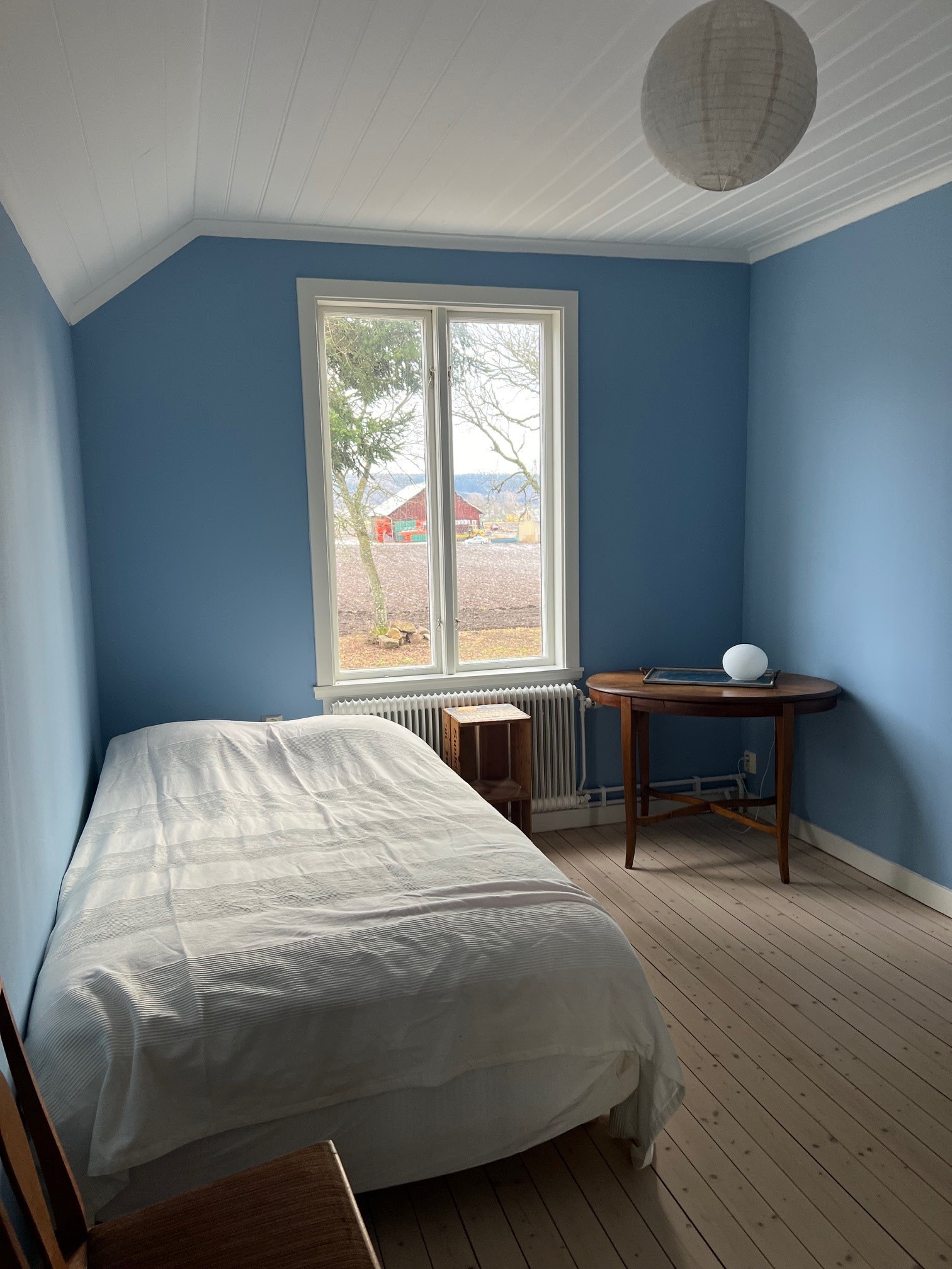Ett sovrum på första våning med en enkelsäng. Blå väggar.