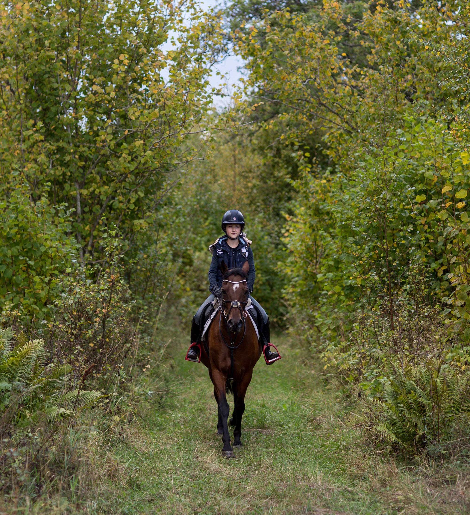 en tjej som rider på en häst i skogen