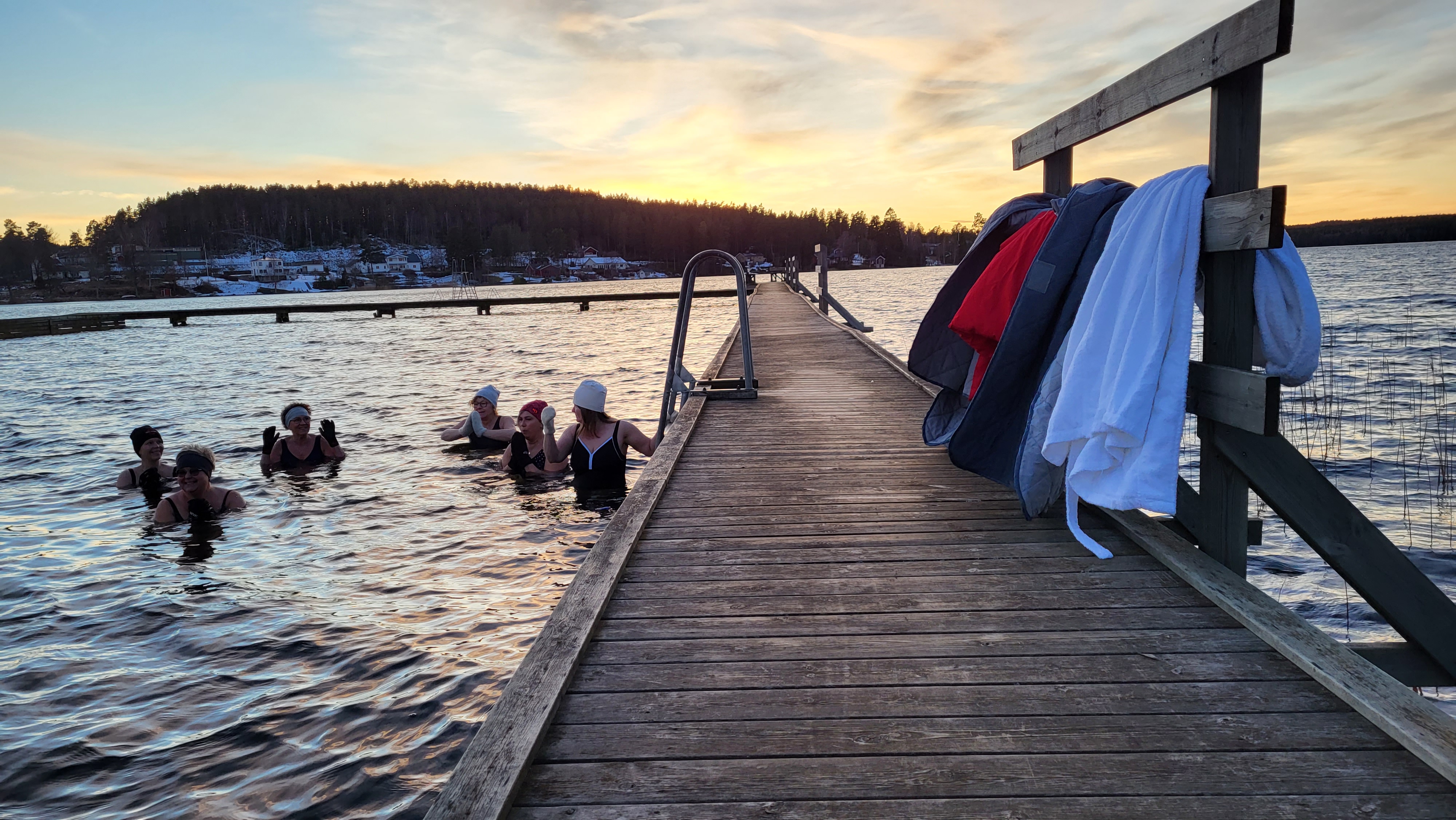 Damer badar, morgonrockar hänger på bryggan 