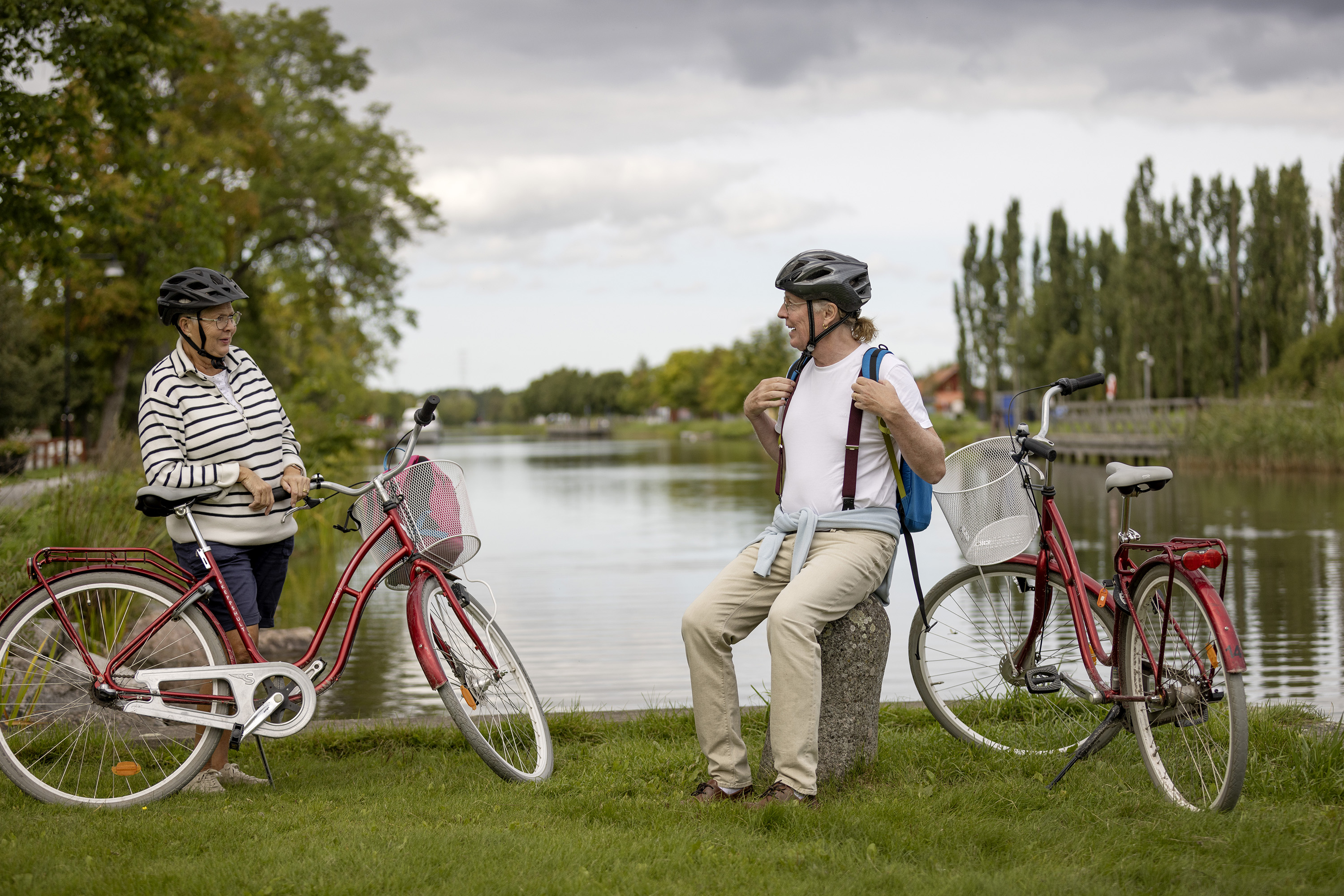 Ett par som vilar i närheten av sina cyklar. I bakgrunden syns ett vattendrag