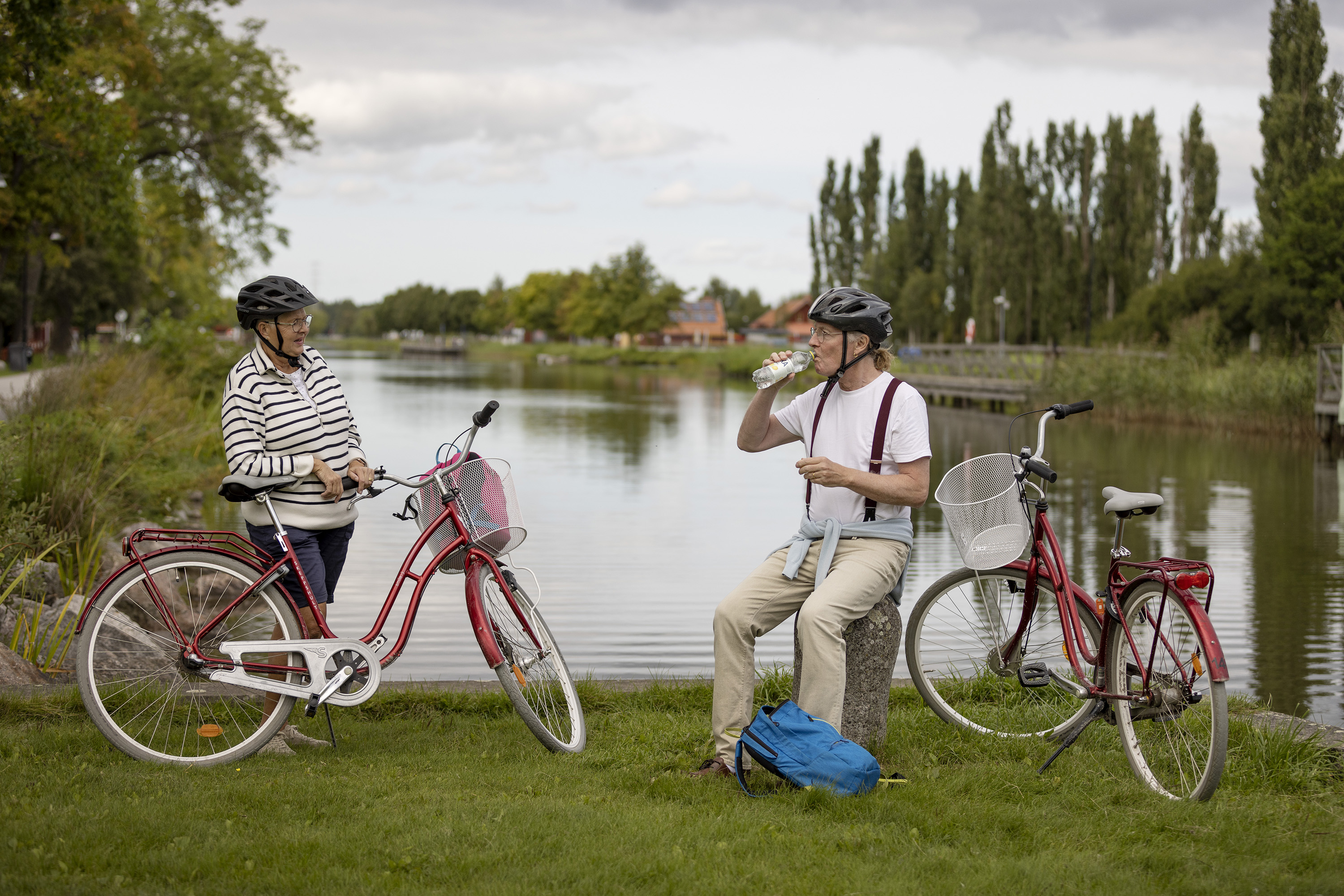 Ett par som vilar i närheten av sina cyklar. I bakgrunden syns ett vattendrag