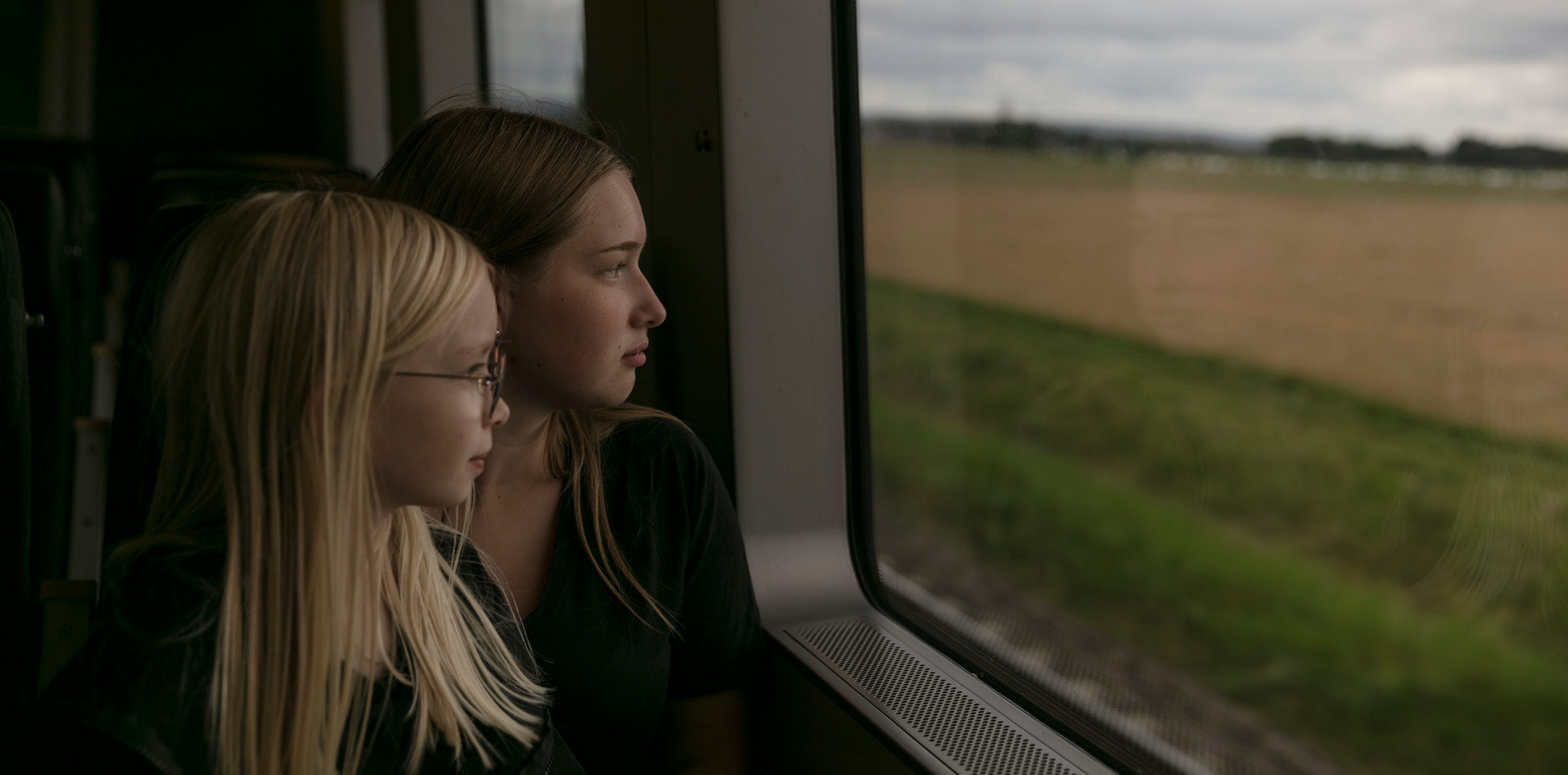 Två tjejer som sitter i en tågkupé och tittar ut genom fönstret