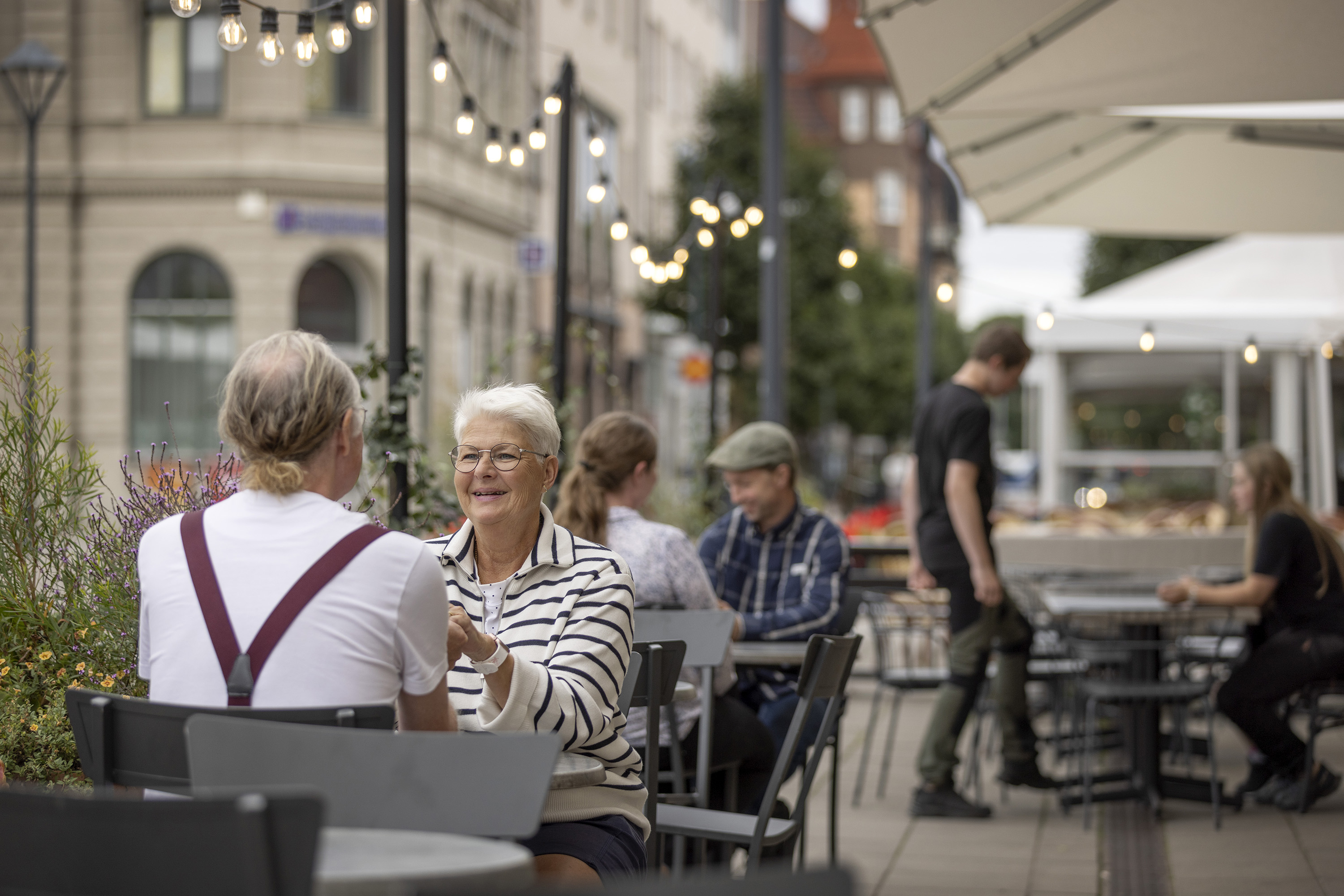 Några personer sitter vid bord på en uteservering.