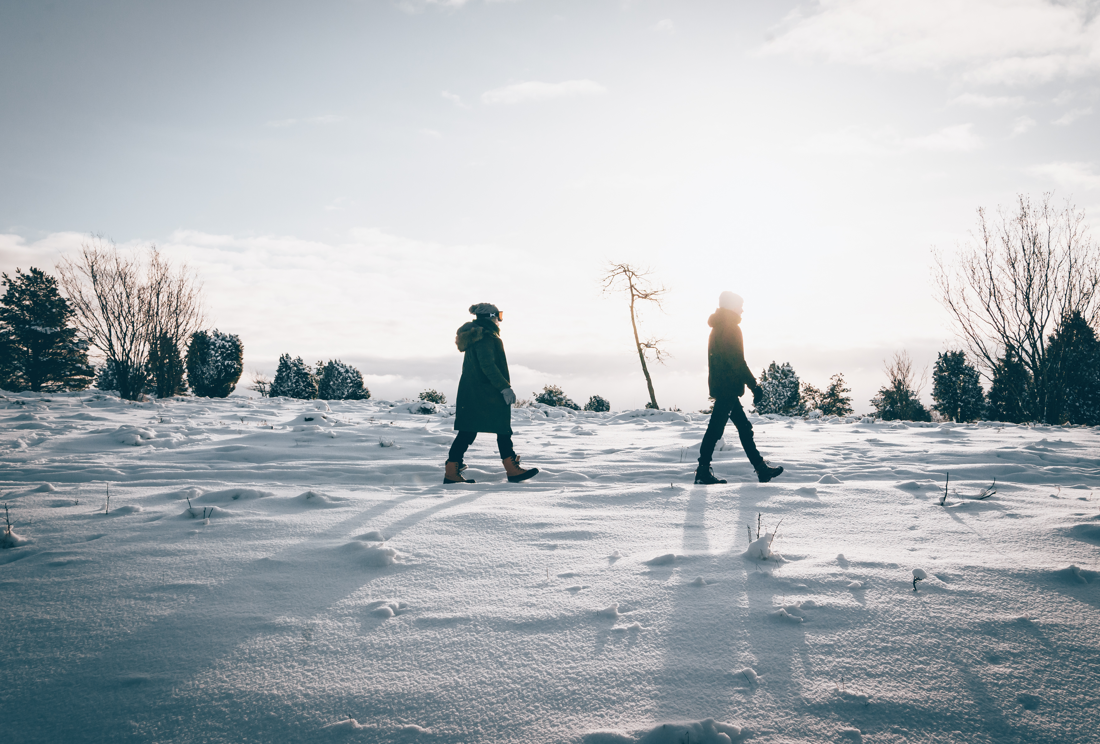 Två personer som är ute och går på ett berg med snö. Solen lyser.