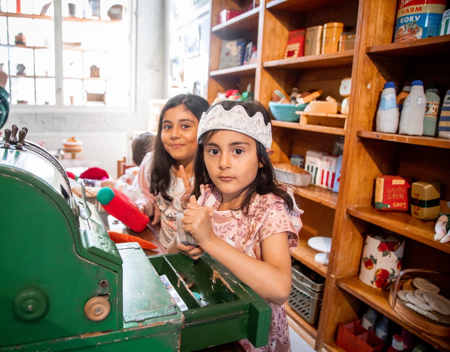 Två flickor leker affär i Tidaholms Barnens hus. De är utklädda till prinsessor.
