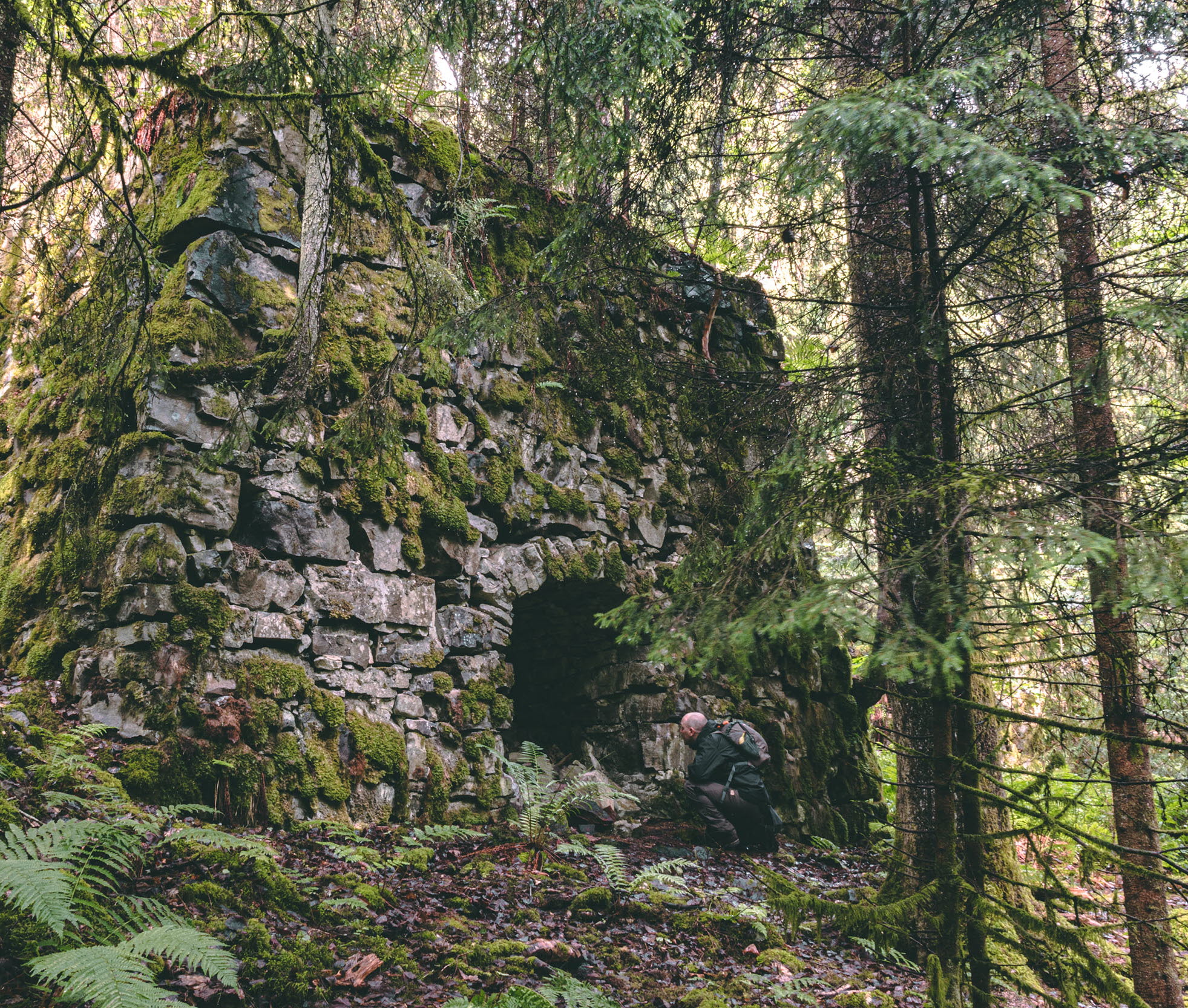 En stenbyggnad med öppen ingång i skogen