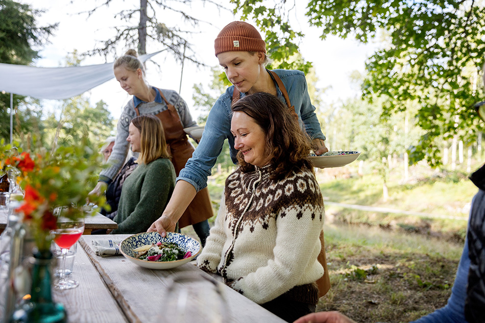 A woman in brown curly hair is served food on a blue-flowered plate.