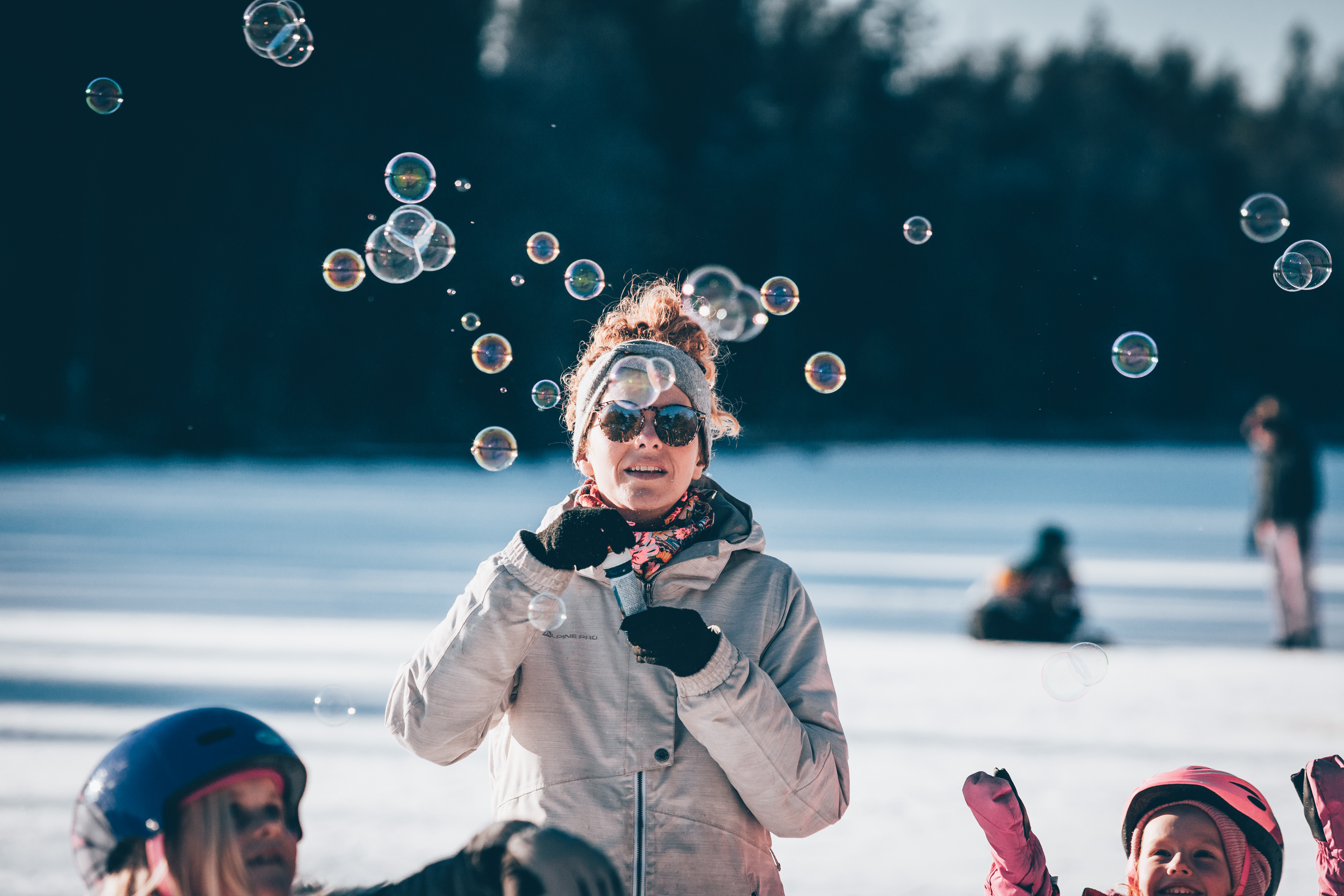 En kvinna blåser såpbubblor på en frusen sjö